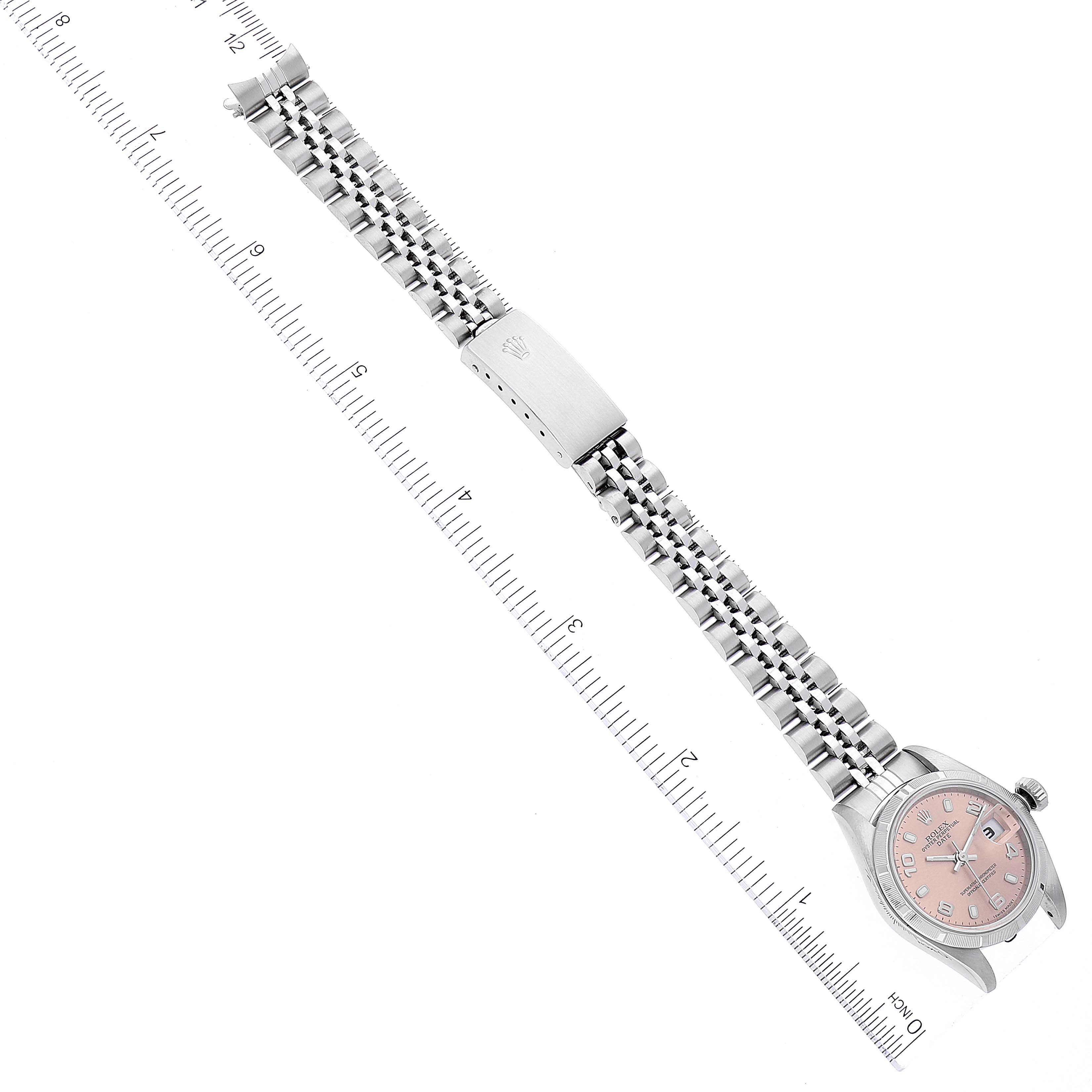 This image shows a top view of a Rolex Date 79190 Women's Stainless Steel Pink Dial 79190 Women's Stainless Steel Pink Dial model watch with its full bracelet extended next to a ruler.