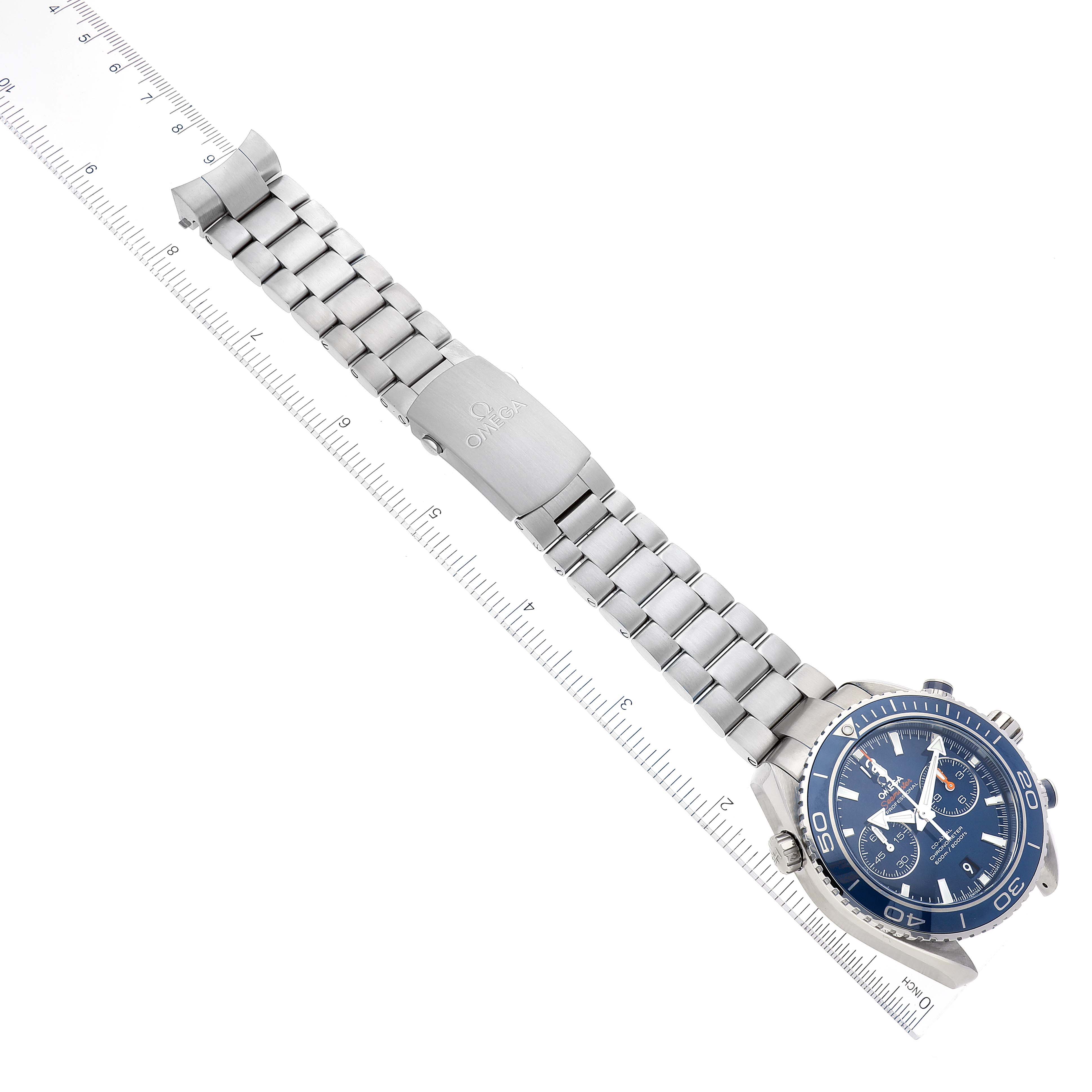 The Omega Planet Ocean 232.90.46.51.03.001 Men's Titanium Blue Dial 232.90.46.51.03.001 Men's Titanium Blue Dial watch is shown from above, displaying its full bracelet, clasp, and face aligned alongside a ruler.