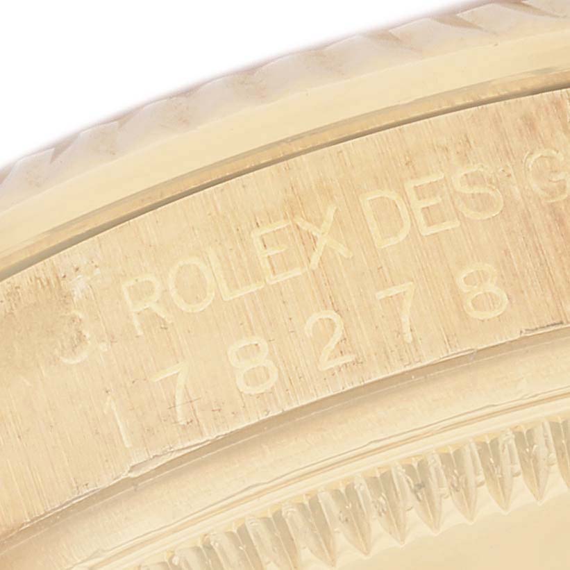 This close-up image shows the edge of the case with engraved text of a Rolex President 178278 Women's Yellow Gold Black Dial 178278 Women's Yellow Gold Black Dial model watch.