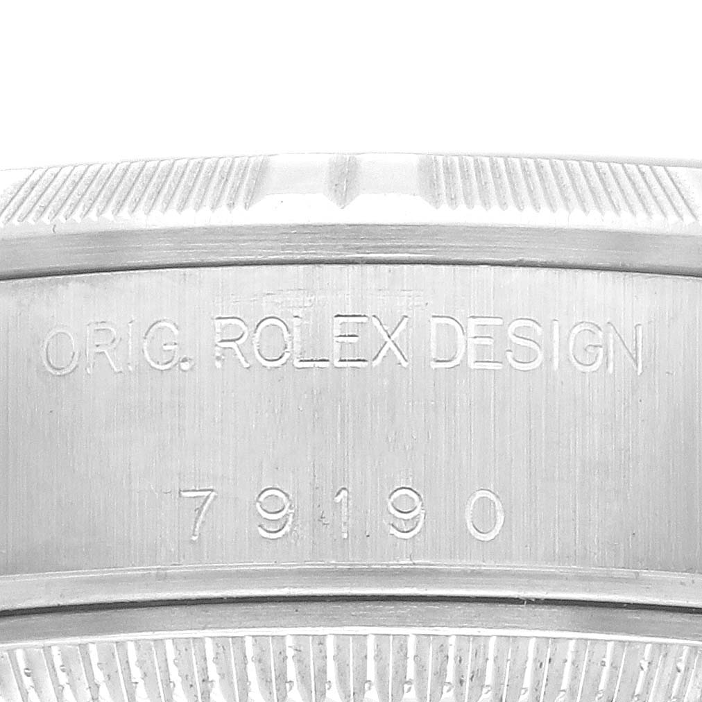 The image shows the engraved bezel or case edge of a Rolex Date 79190 Women's Stainless Steel Silver Dial 79190 Women's Stainless Steel Silver Dial model watch, focusing on its serial number and design inscription.