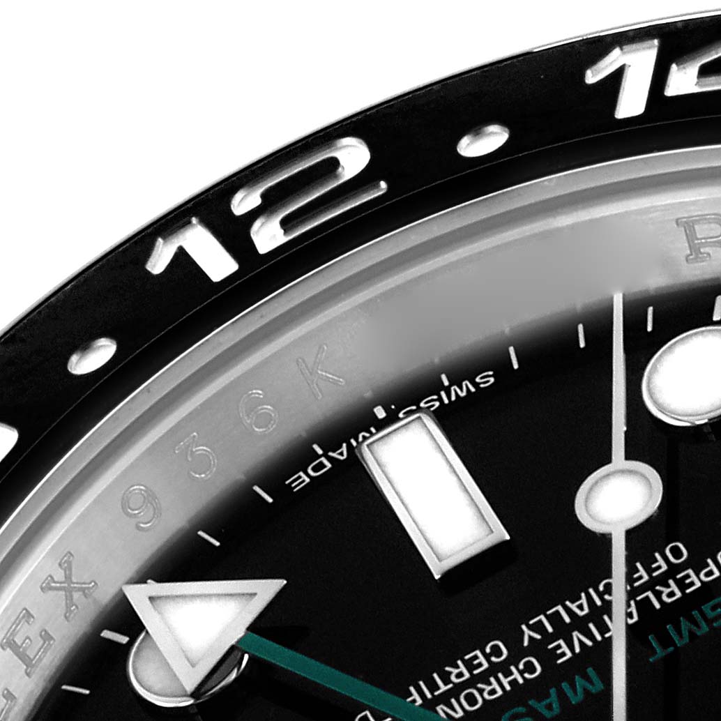 The image shows a close-up of the Rolex GMT-Master 116710LN Men's Stainless Steel Black Dial 116710LN Men's Stainless Steel Black Dial's bezel, dial, and part of the hands at an angle highlighting the 12 o'clock mark.