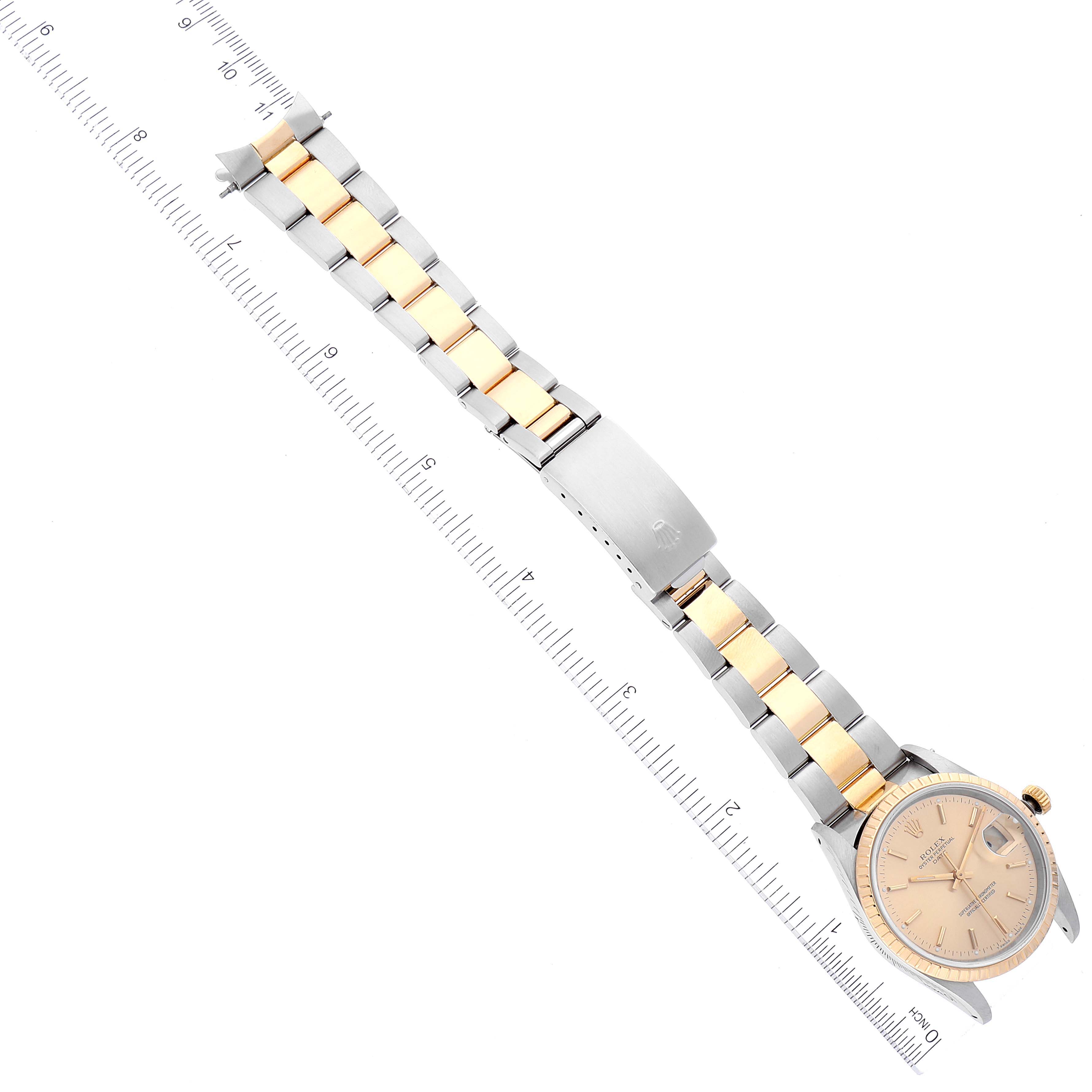 The image shows the entire Rolex Date 15223 Men's Steel and Gold (two tone) Champagne Dial 15223 Men's Steel and Gold (two tone) Champagne Dial model watch, including the face, bezel, and two-tone bracelet, laid flat next to a ruler.