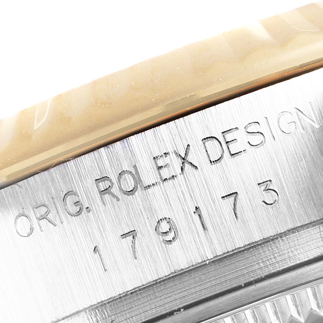 This close-up image shows the engraved serial number and "ORIG. ROLEX DESIGN" text on the case of a Rolex Datejust 179173 Women's Steel and Gold (two tone) Champagne Dial 179173 Women's Steel and Gold (two tone) Champagne Dial watch.
