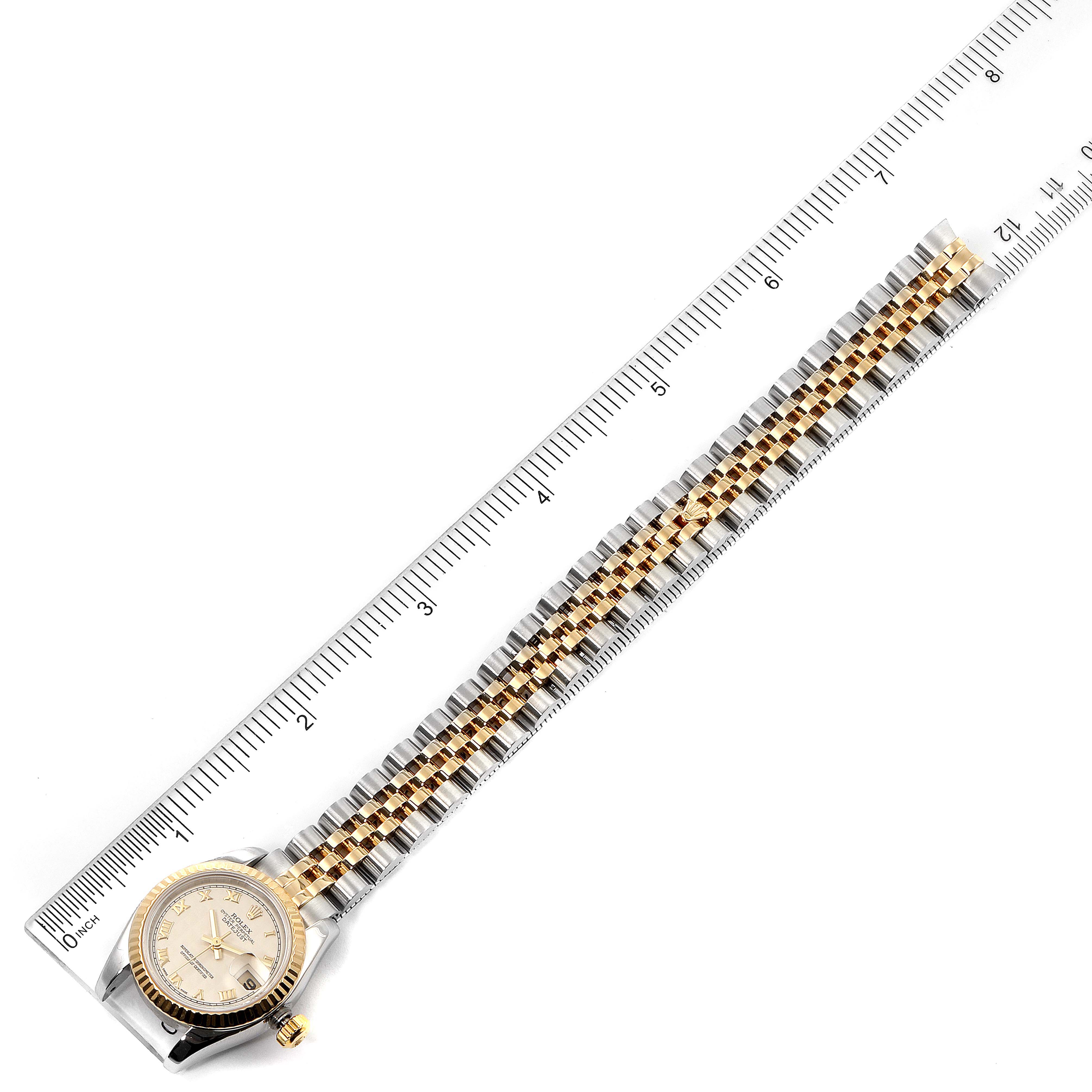 The image shows the front view of a Rolex Datejust 179173 Women's Steel and Gold (two tone) Silver Dial 179173 Women's Steel and Gold (two tone) Silver Dial watch, including the face and bi-metal bracelet, positioned next to a ruler.