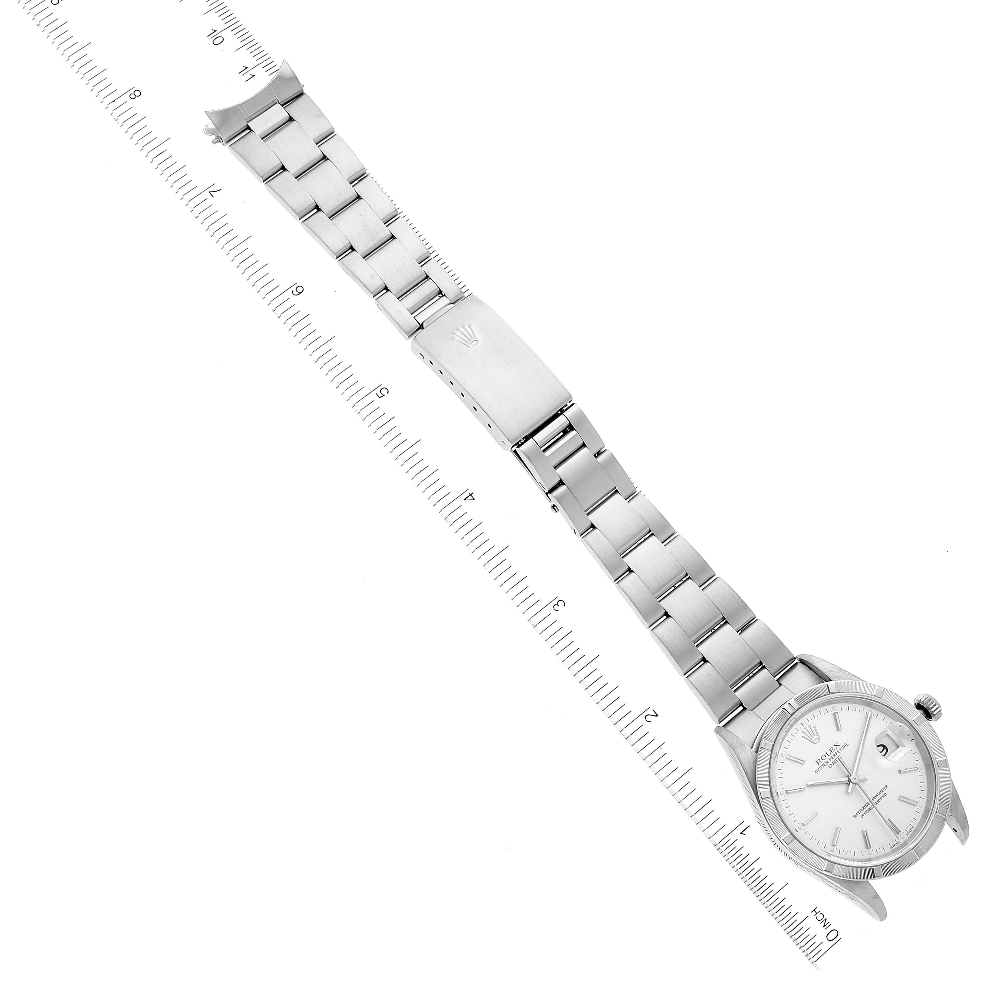 The image shows a top-down view of a Rolex Date 15210 Men's Stainless Steel Silver Dial 15210 Men's Stainless Steel Silver Dial model watch, displaying the face, bracelet, and clasp next to a ruler.