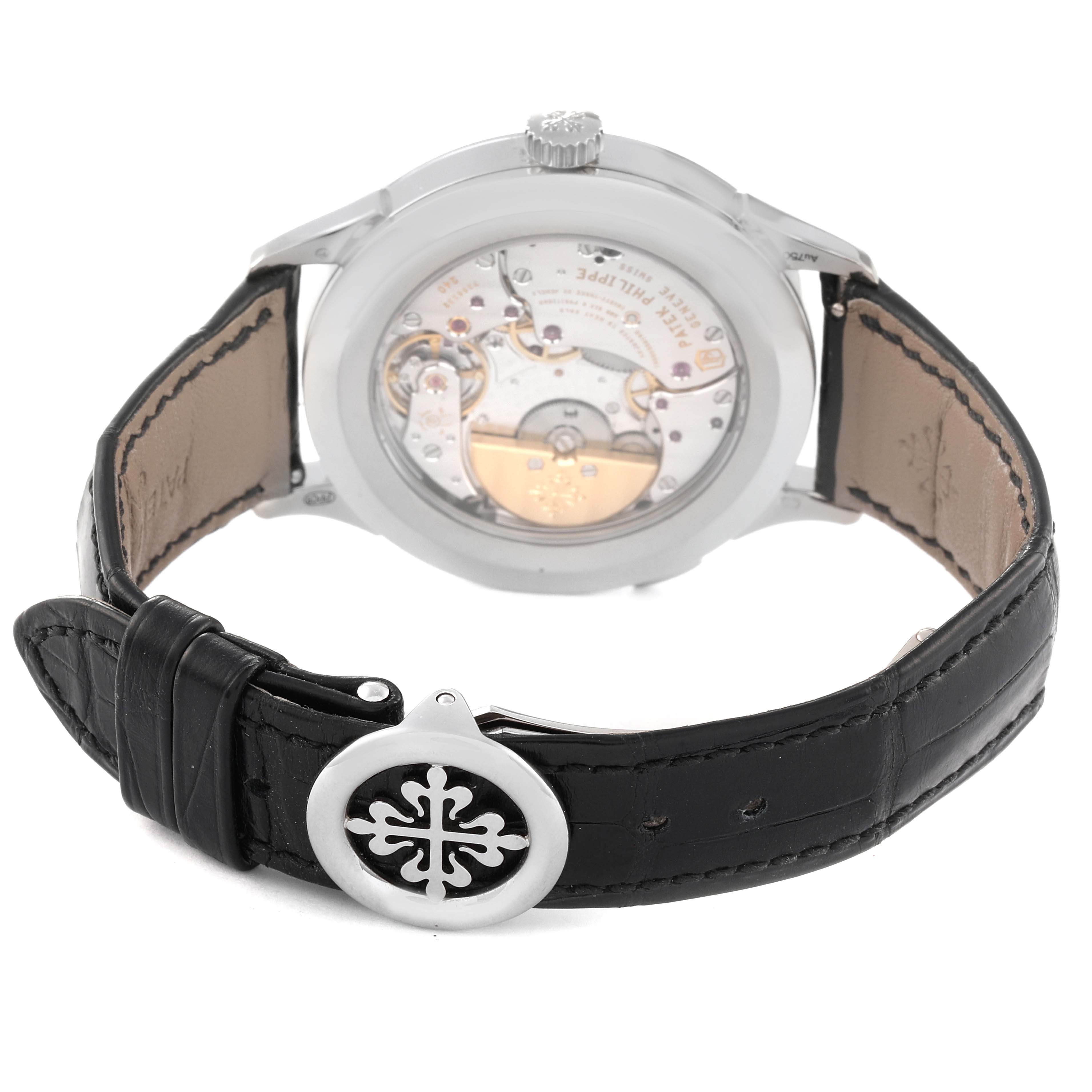 This image shows the back case and movement of a Patek Philippe Complications 5230G-001 Men's White Gold Grey Dial 5230G-001 Men's White Gold Grey Dial watch, along with its leather strap and buckle.