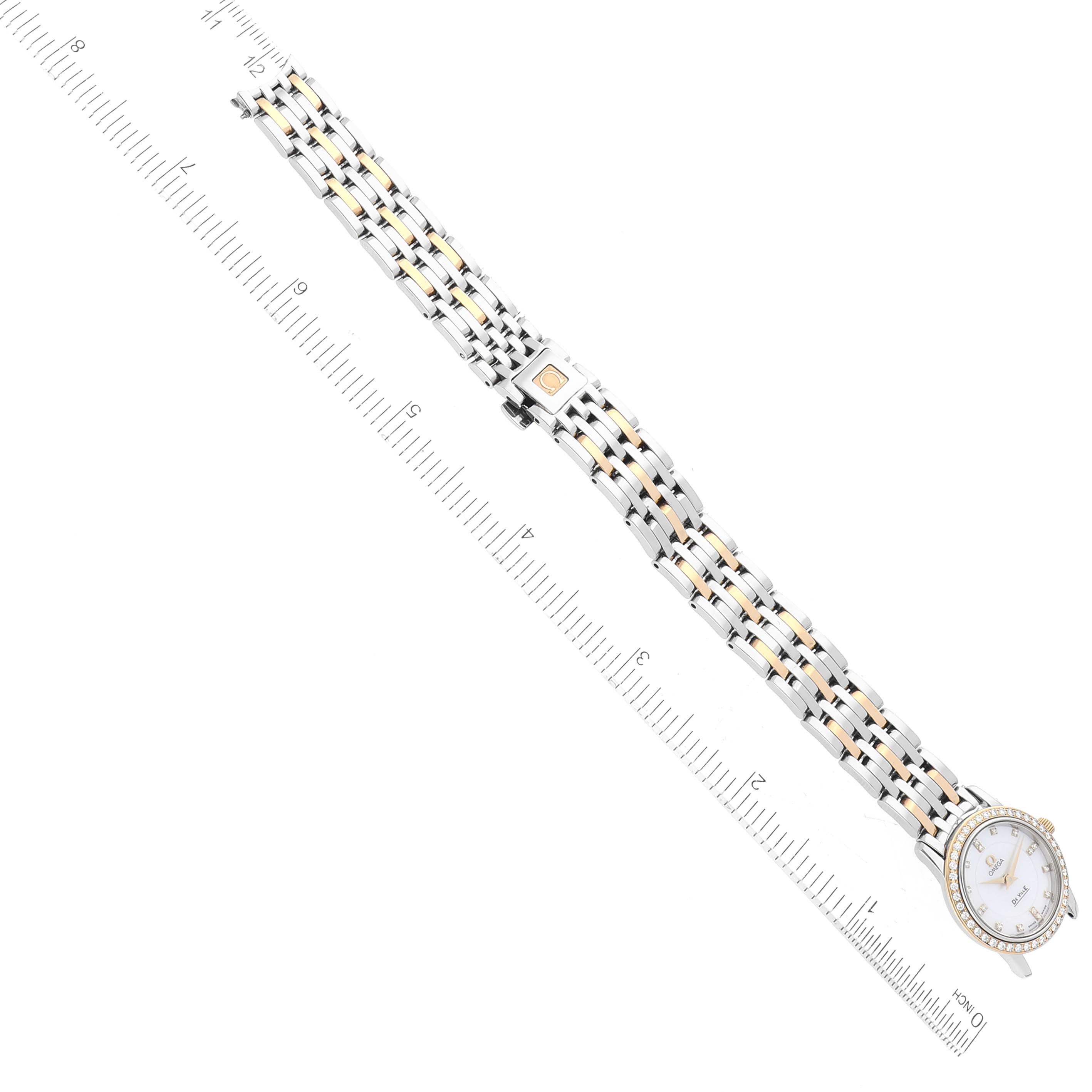The Omega 4375.75.00 Women's Steel and Gold (two tone) Mother of Pearl Dial 4375.75.00 Women's Steel and Gold (two tone) Mother of Pearl Dial DeVille Mother Of Pearl Diamond Steel Yellow Gold Ladies Watch 4375.75.00 is shown laid flat with a ruler for scale.