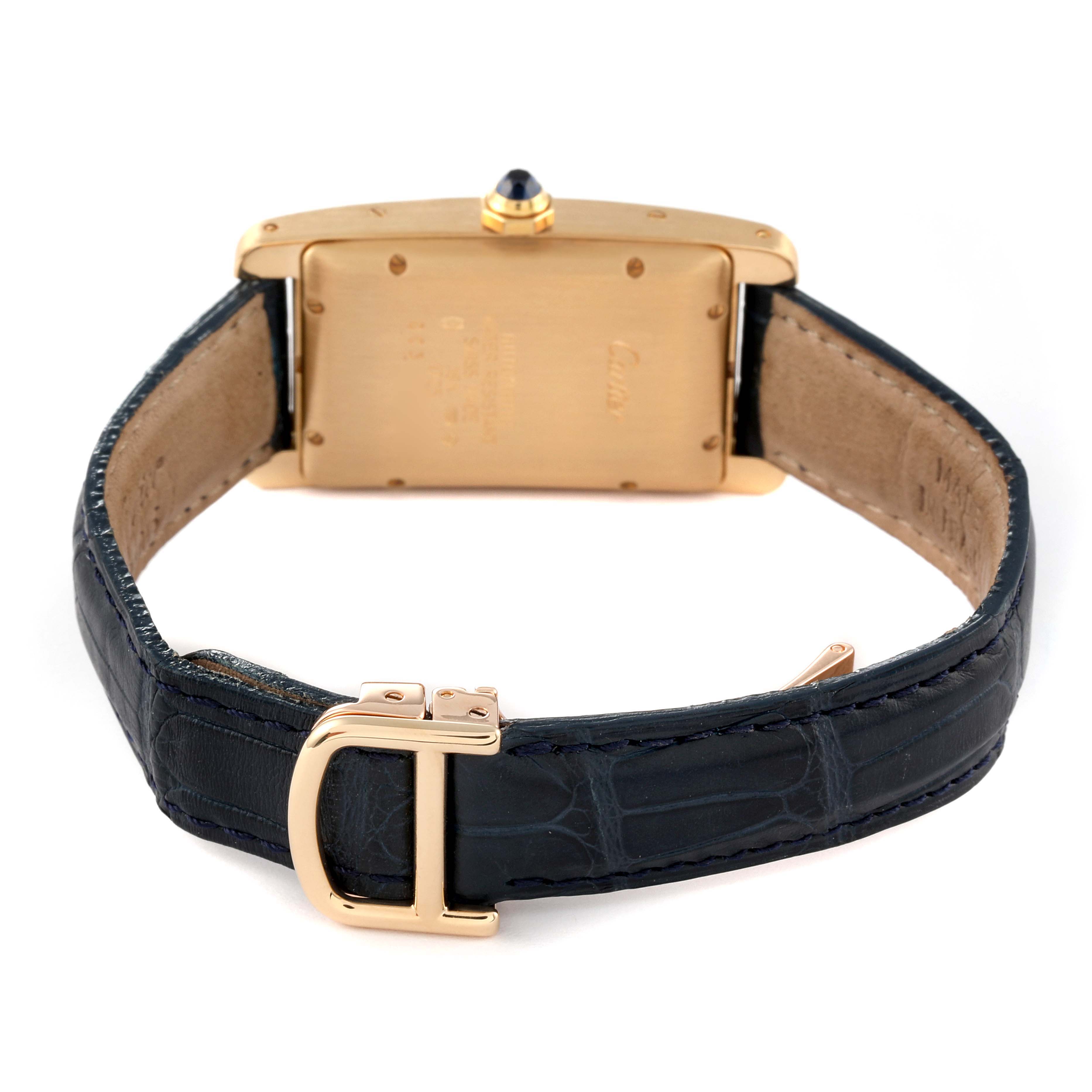 The image shows the back view of a Cartier Tank Americaine W2603556 Men's Yellow Gold Silver Dial W2603556 Men's Yellow Gold Silver Dial watch, highlighting the case, strap, buckle, and crown with a blue cabochon.