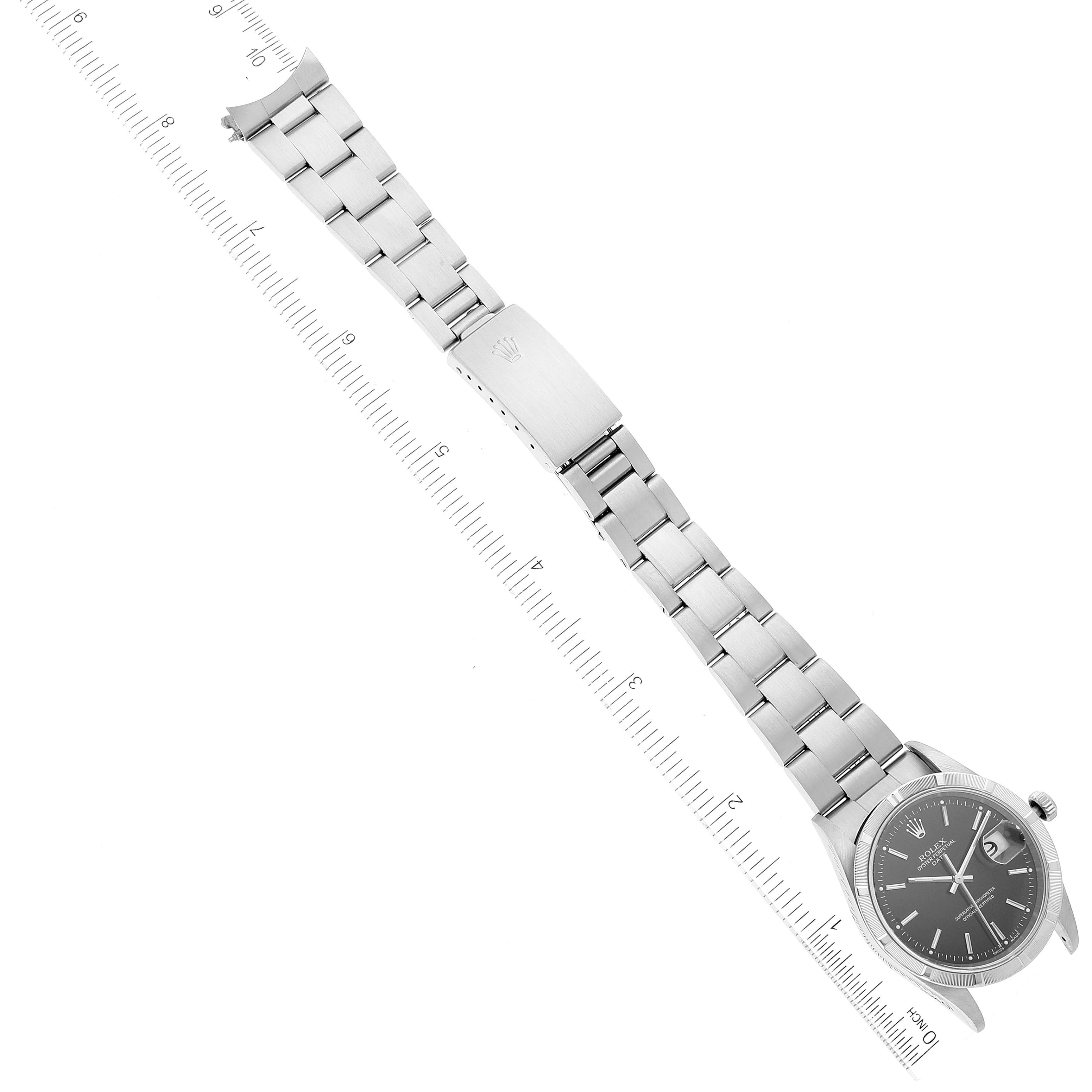 The image shows a Rolex Date 15210 Men's Stainless Steel Black Dial 15210 Men's Stainless Steel Black Dial model watch laid flat, displaying the face, bracelet, and clasp with a ruler for scale.