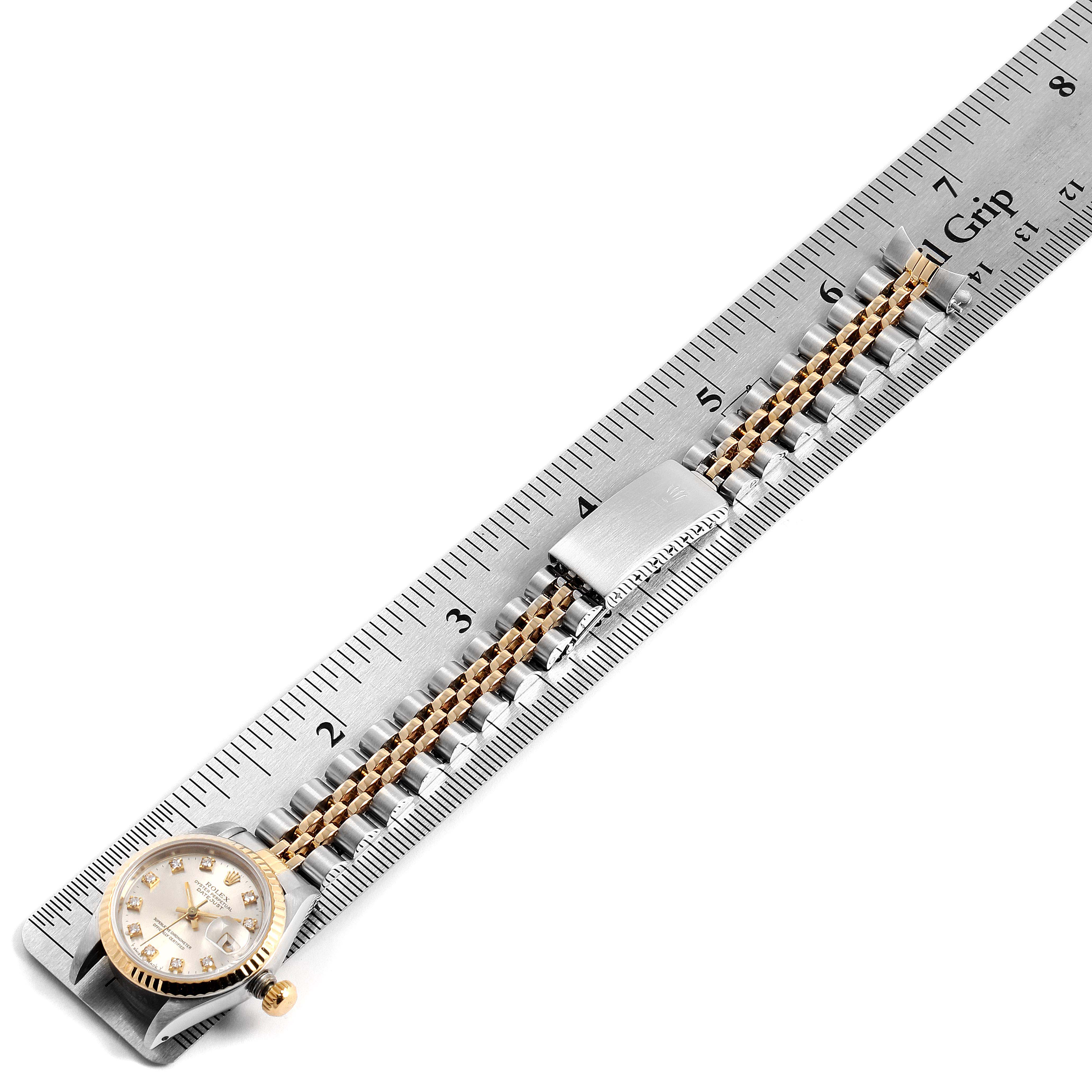 The Rolex Datejust 69173 Women's Steel and Gold (two tone) Silver Dial 69173 Women's Steel and Gold (two tone) Silver Dial watch is shown from a top-down angle with its face, bezel, and bracelet visible alongside a ruler.