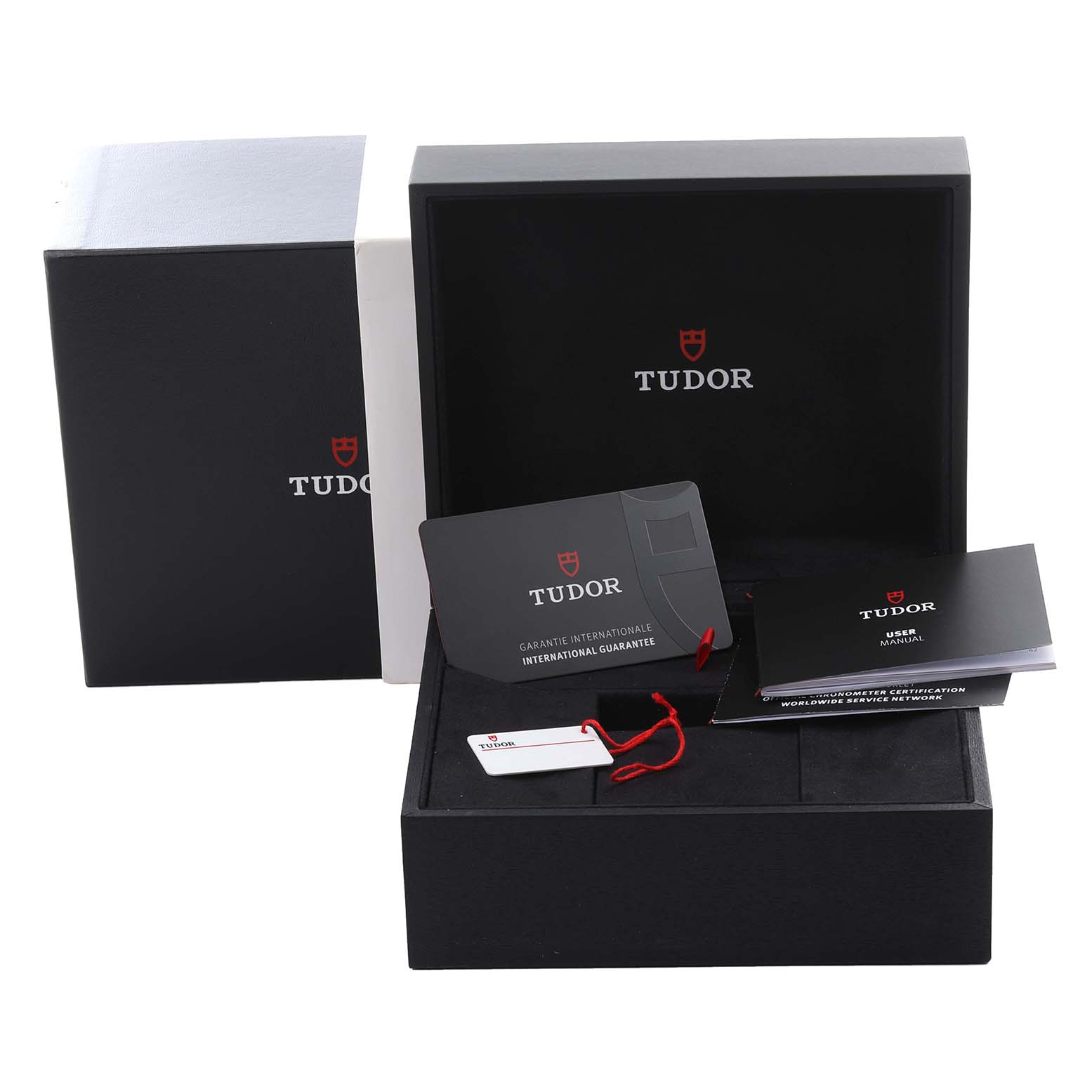 The Tudor Heritage Chrono 79360N-0001 Men's Stainless Steel Black Dial 79360N-0001 Men's Stainless Steel Black Dial watch box is shown at eye level, with a warranty card, tag, and manual displayed.