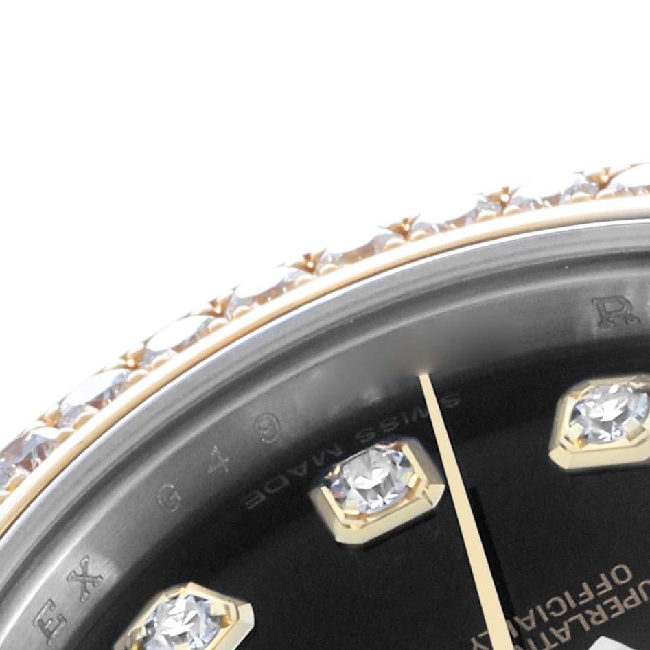 This close-up of the Rolex Datejust 179383 Women's Steel and Gold (two tone) Black Dial watch shows part of the bezel with diamonds, index markers, and the minute hand.