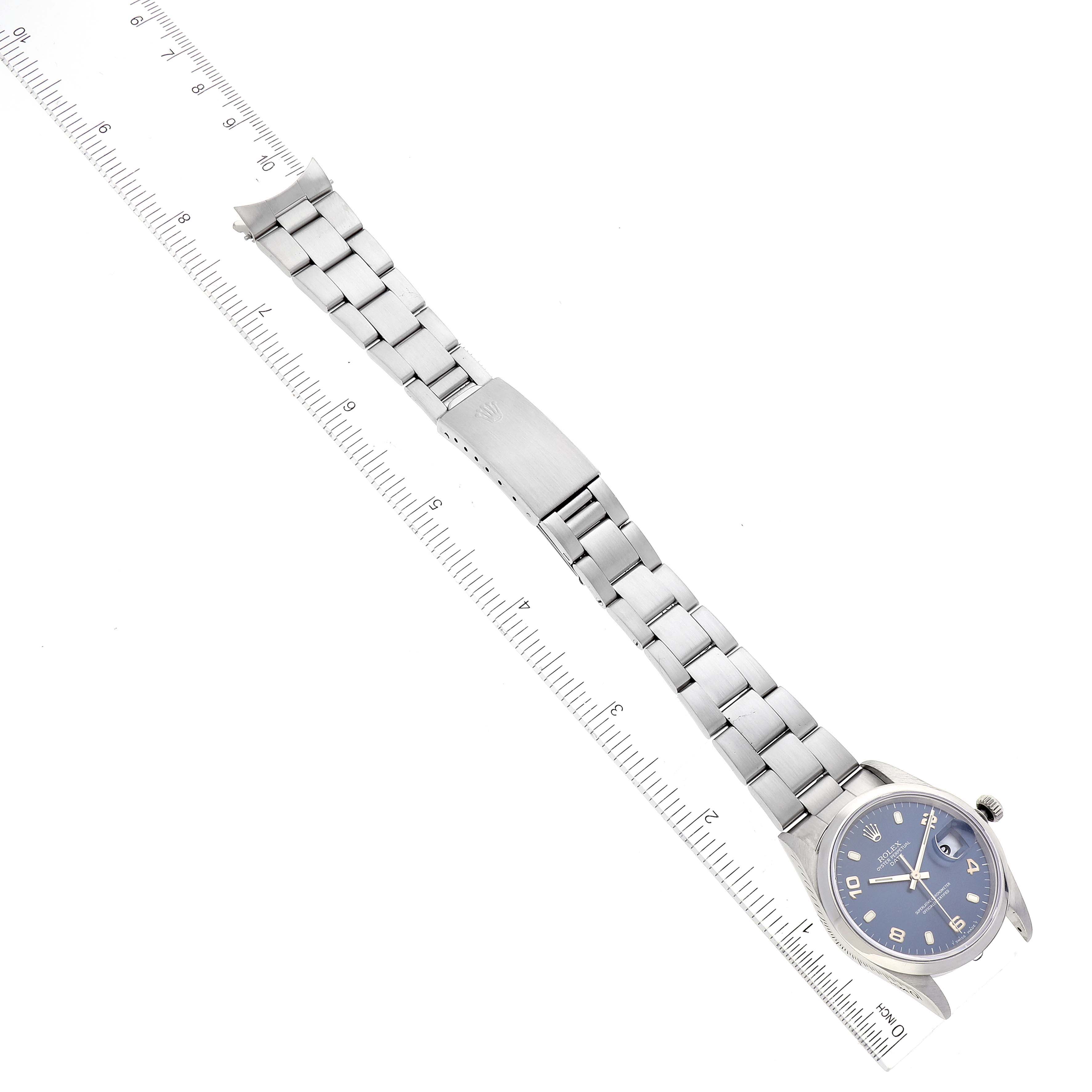 The image shows a top-down angle of a Rolex Date 15200 Men's Stainless Steel Blue Dial 15200 Men's Stainless Steel Blue Dial model watch, showcasing the entire band and face next to a ruler for scale.