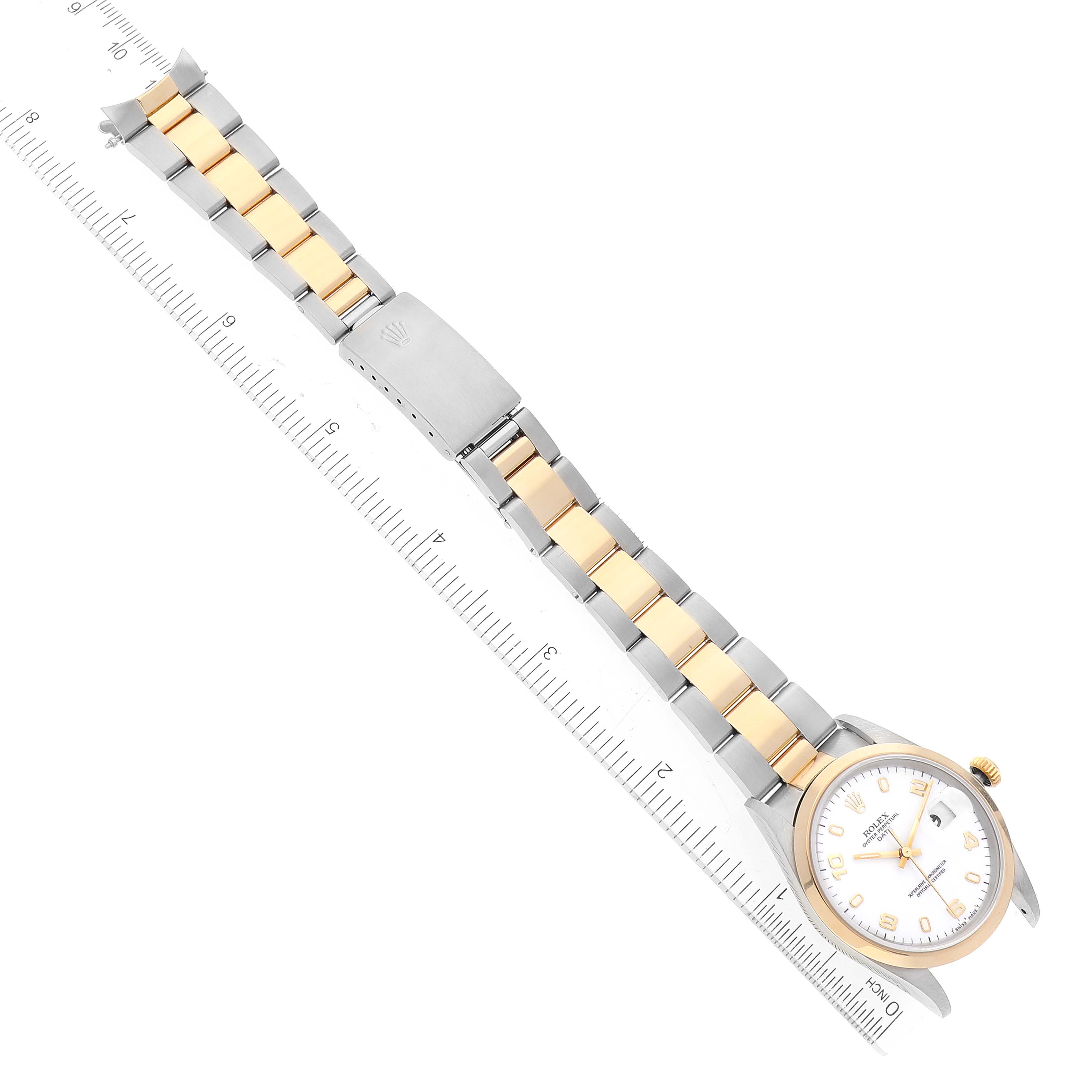 The image shows a Rolex Date 15203 Men's Steel and Gold (two tone) White Dial 15203 Men's Steel and Gold (two tone) White Dial model watch at an oblique angle, fully extended with the face and bracelet visible, next to a ruler for scale.