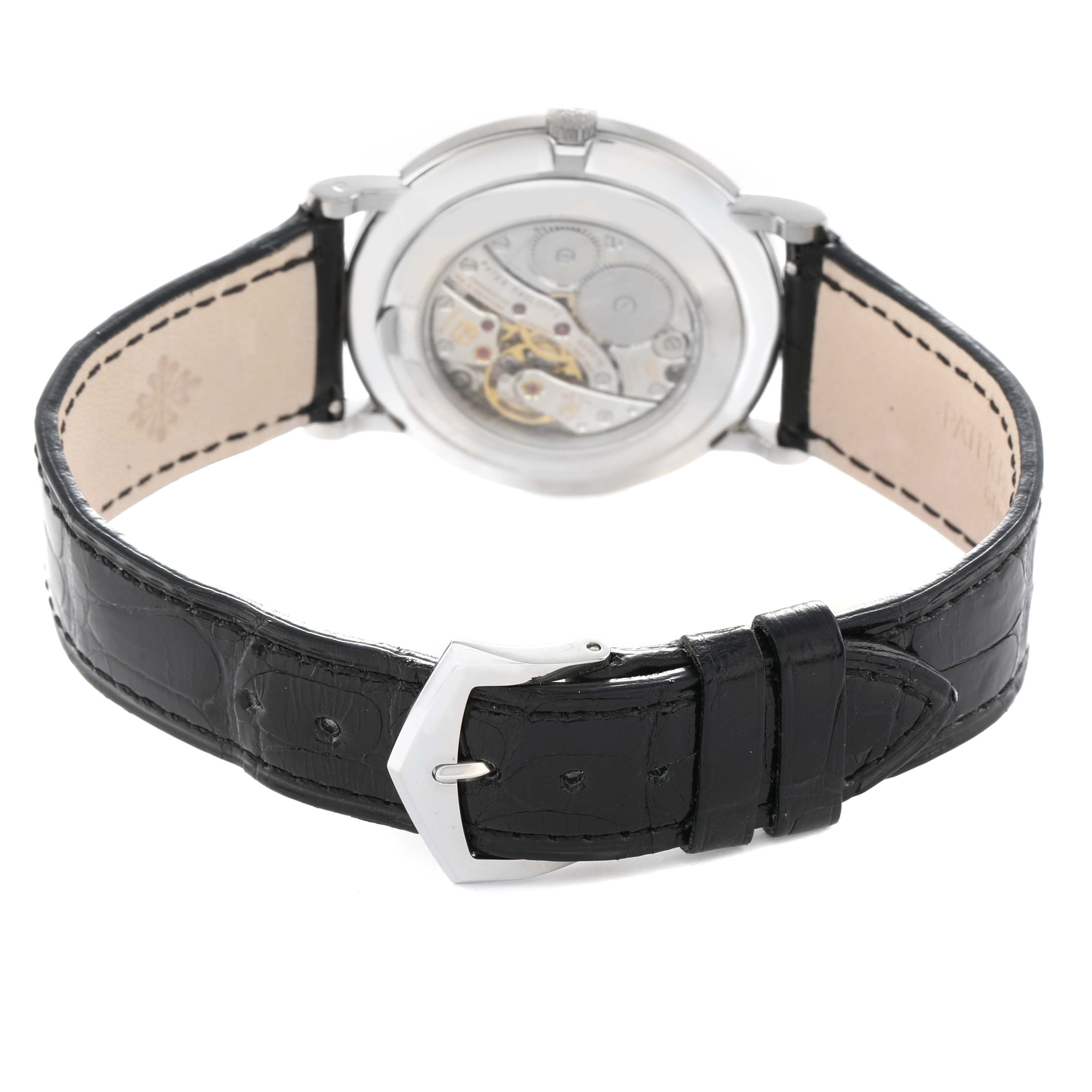 The image shows the back view of a Patek Philippe Calatrava 5119G Men's White Gold White Dial, highlighting the movement and black leather strap with buckle.