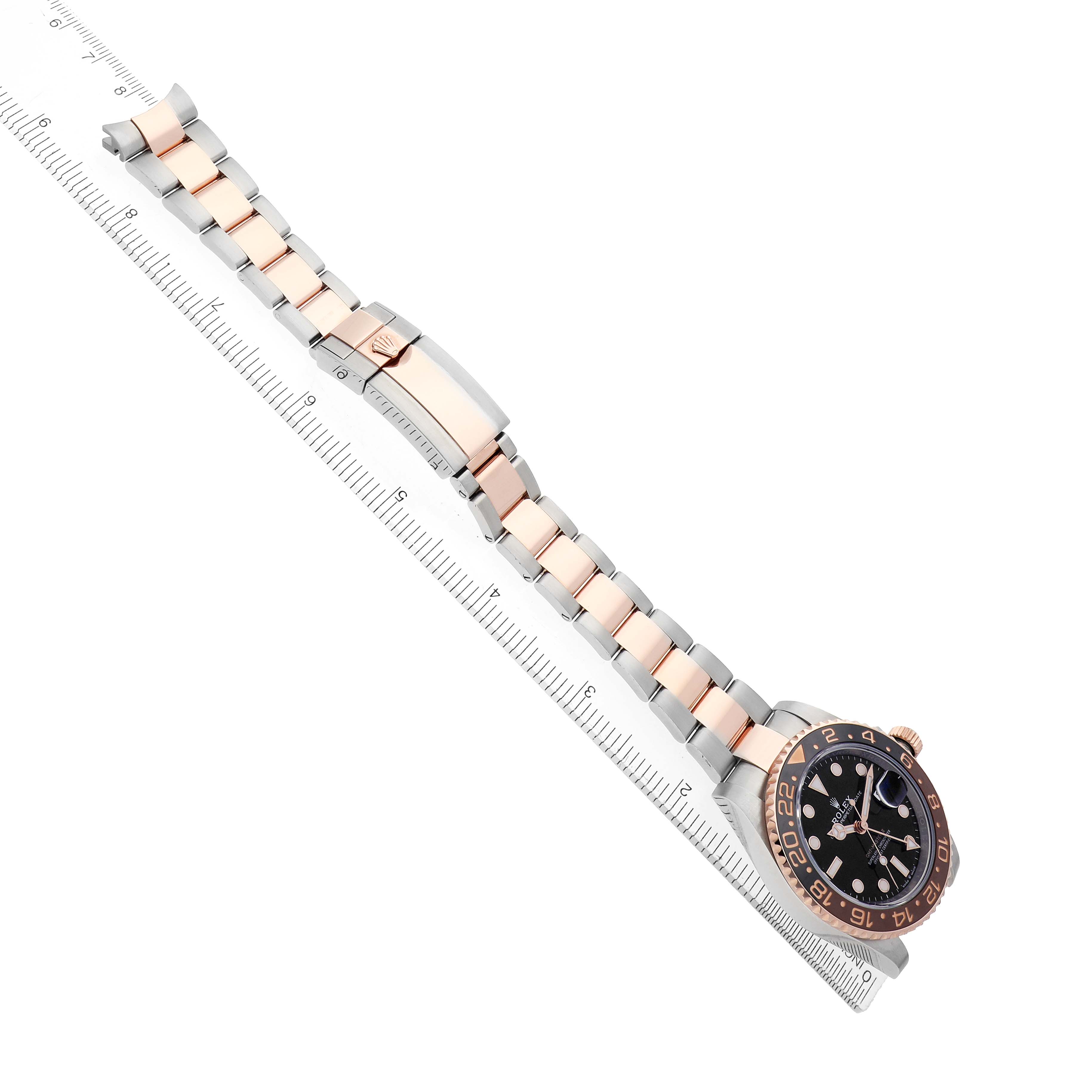 The Rolex GMT-Master 126711 Men's Steel and Gold (two tone) Black Dial watch is shown from a top angle, displaying the bracelet, clasp, and face alongside a ruler for scale.