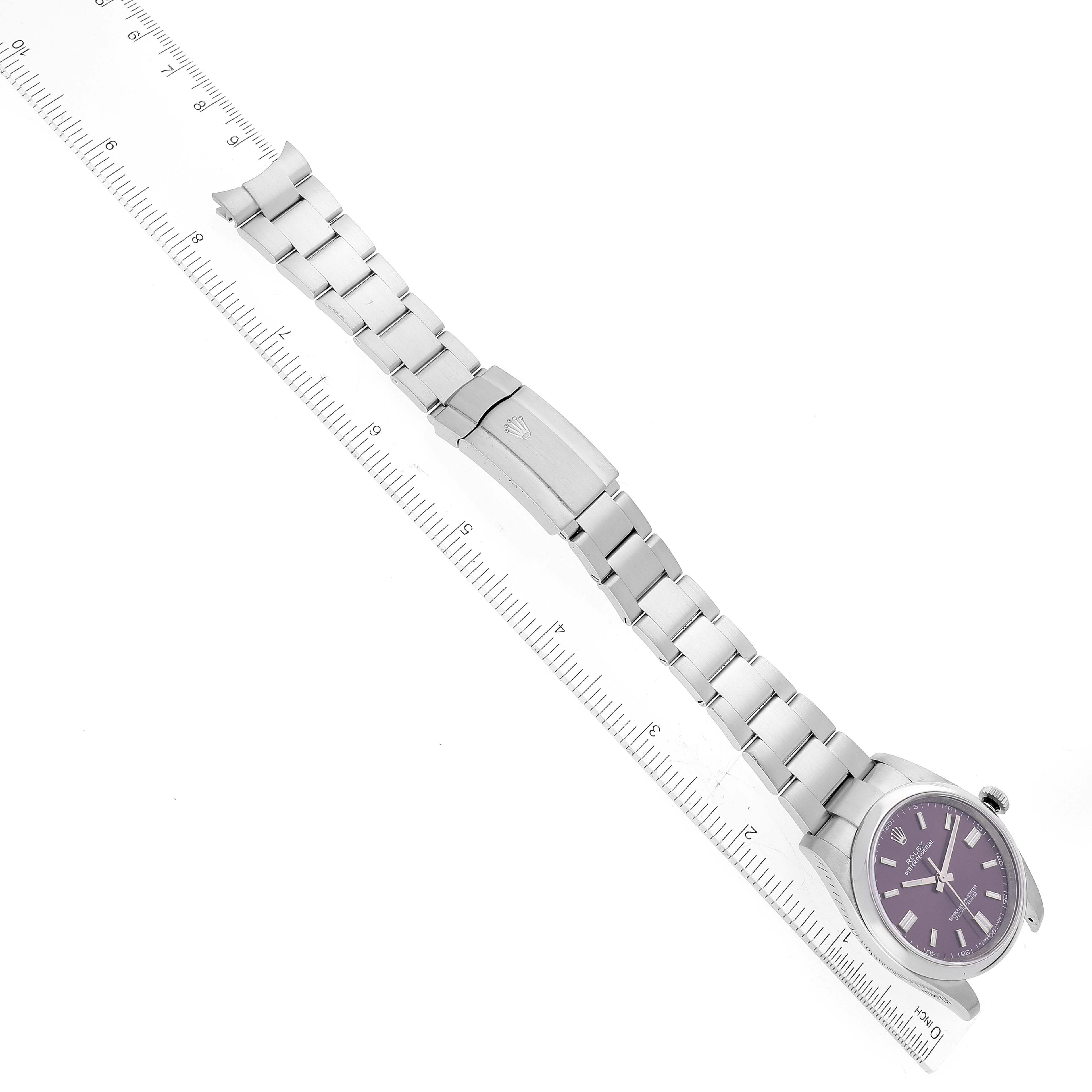The image shows a Rolex Oyster Perpetual 116000 Men's Stainless Steel Purple Dial 116000 Men's Stainless Steel Purple Dial watch and its full bracelet, laid flat alongside a ruler.