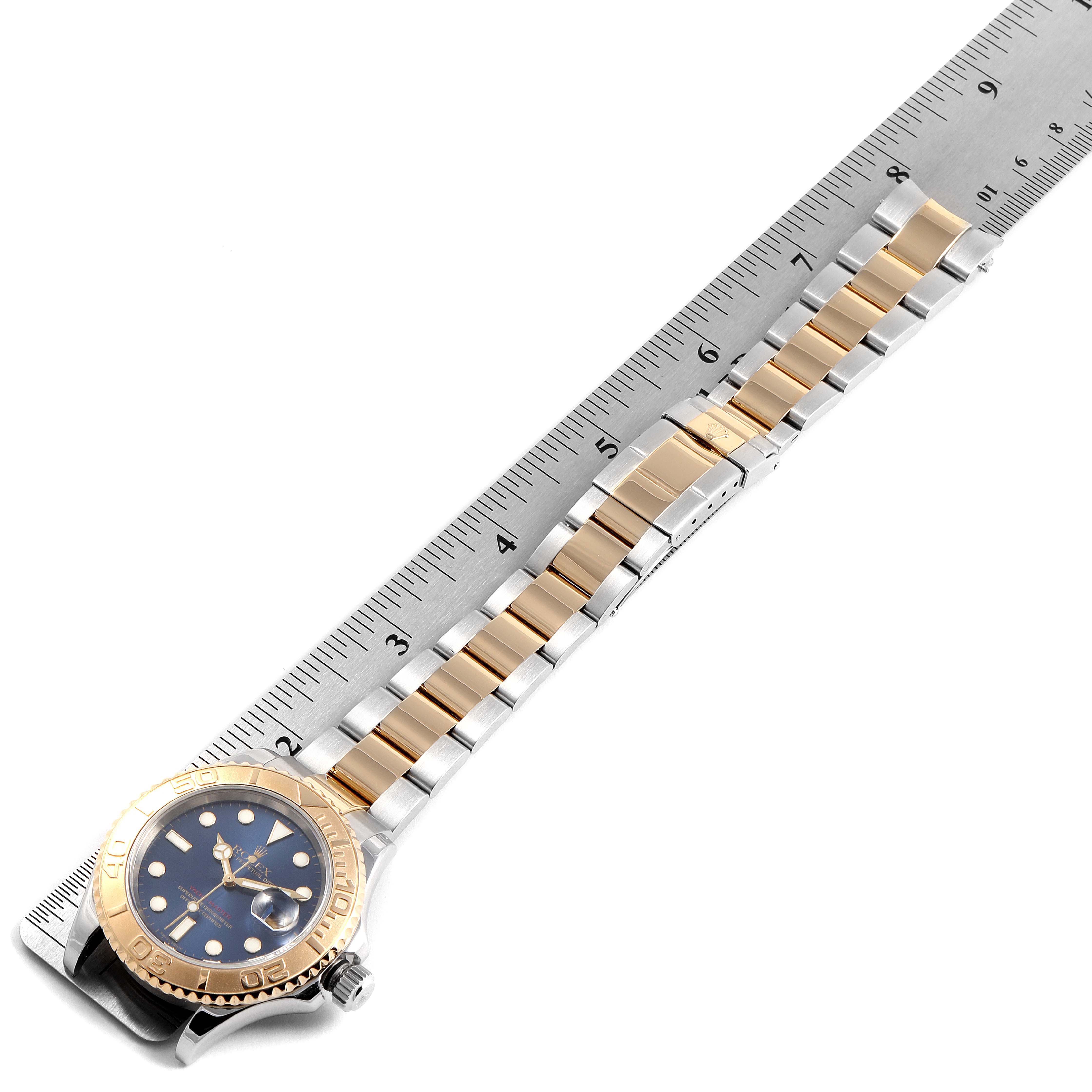 The image shows a Rolex Yacht-Master 16623 Men's Steel and Gold (two tone) Blue Dial 16623 Men's Steel and Gold (two tone) Blue Dial watch from a top-down angle, displaying its face, bezel, and bracelet alongside a ruler.