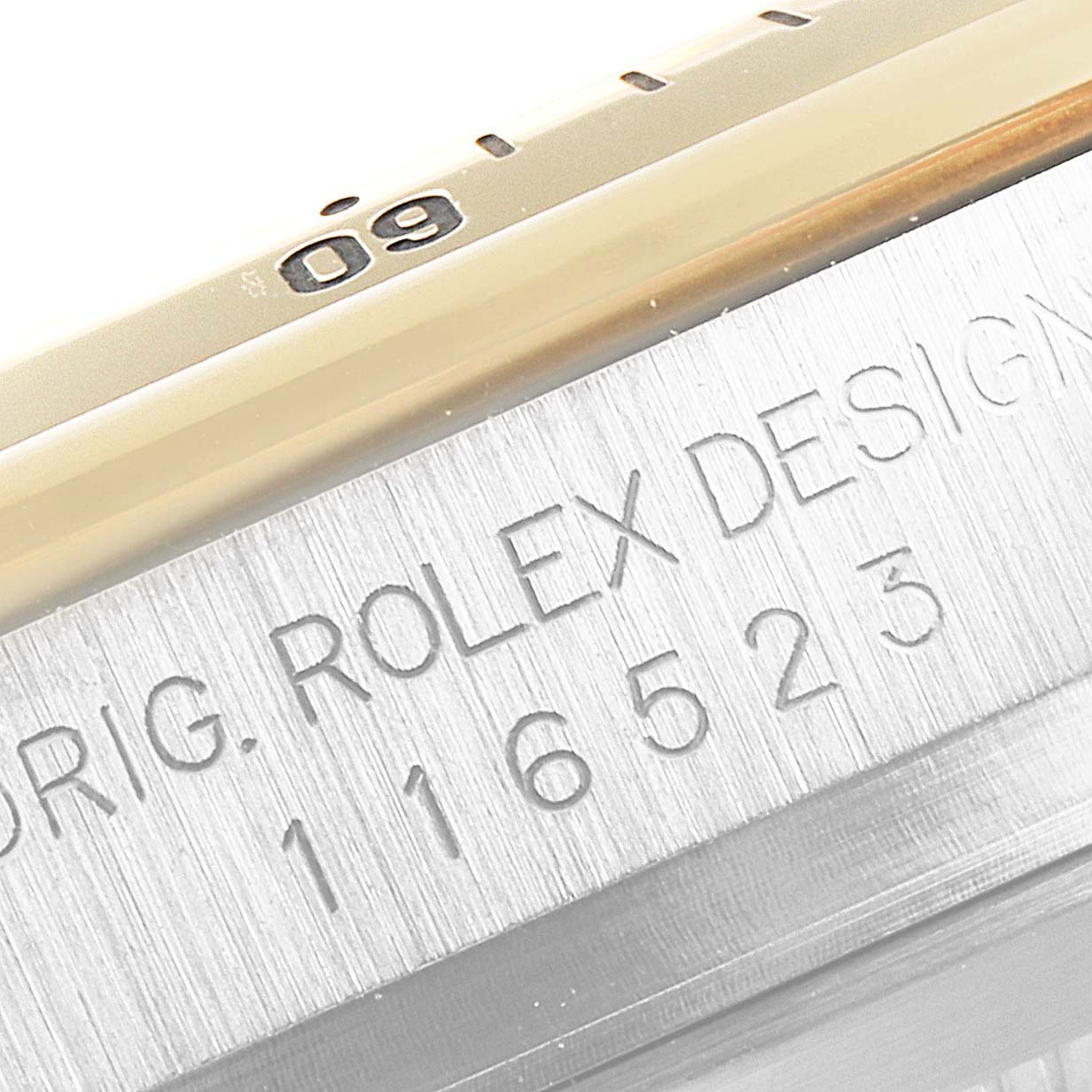 This close-up image shows the side of the Rolex Daytona 116523 Men's Steel and Gold (two tone) Mother of Pearl Dial 116523 Men's Steel and Gold (two tone) Mother of Pearl Dial watch, specifically focusing on the engraved serial number and part of the bezel.