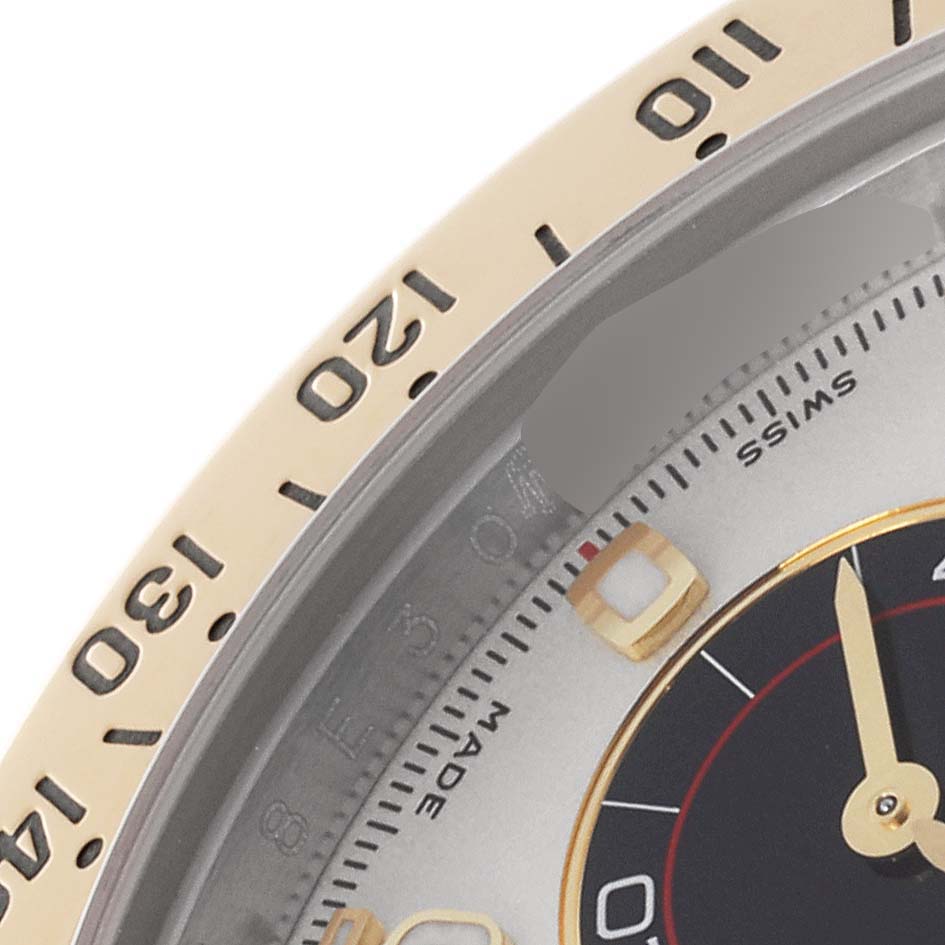 The image shows a close-up of the bezel and part of the dial of the Rolex Daytona 116523 Men's Steel and Gold (two tone) Silver Dial 116523 Men's Steel and Gold (two tone) Silver Dial watch at an angle.