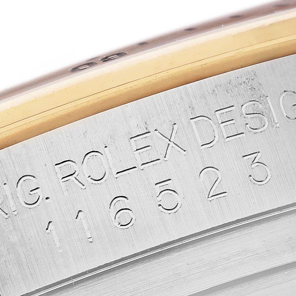 The image shows a close-up of the engraved serial number and "Rolex Design" text on the case side of a Rolex Daytona 116523 Men's Steel and Gold (two tone) Silver Dial 116523 Men's Steel and Gold (two tone) Silver Dial watch.