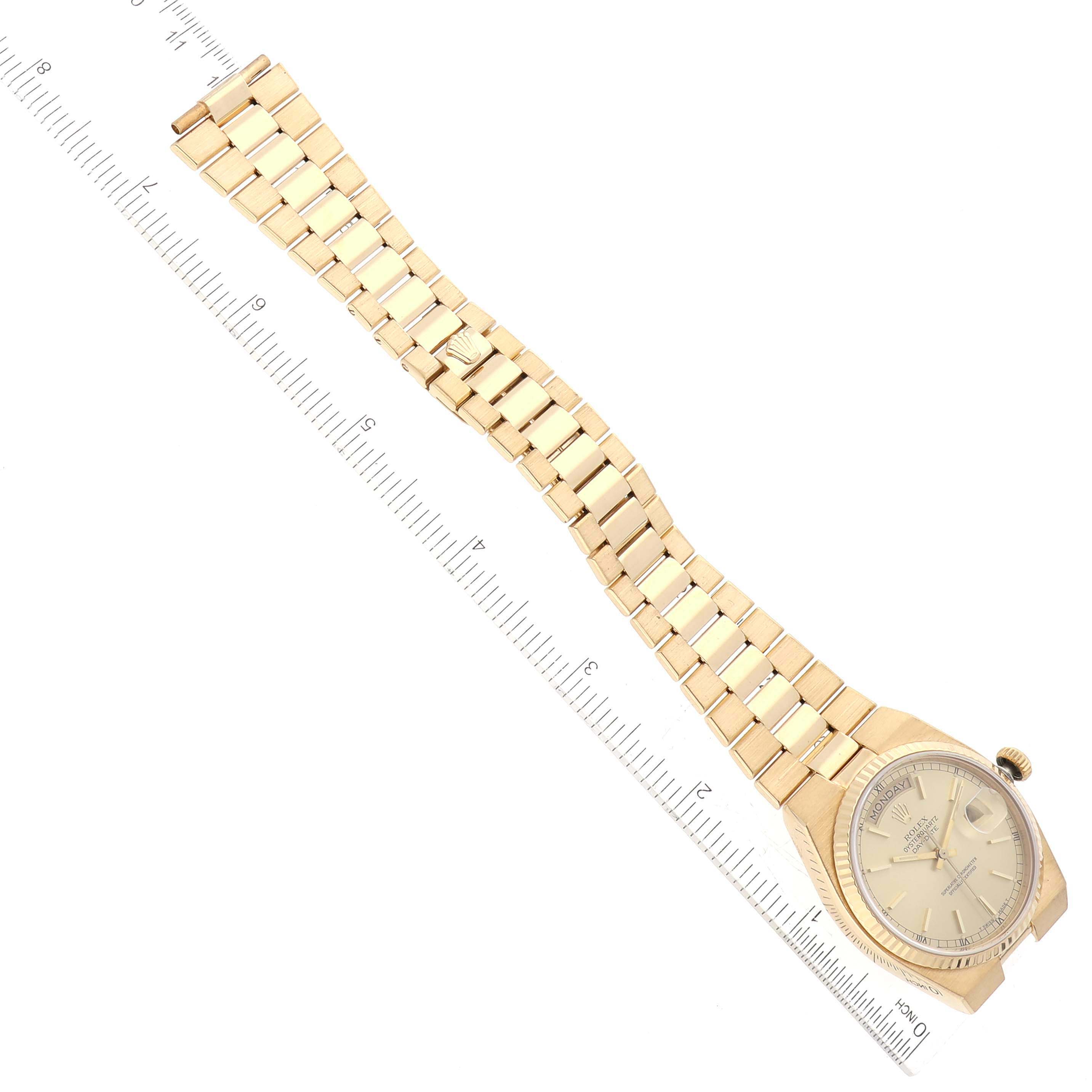 This Rolex Oysterquartz 19018 Men's Yellow Gold Champagne Dial 19018 Men's Yellow Gold Champagne Dial watch is shown from a top-down angle, featuring the face, bracelet, and clasp, alongside a ruler for scale.