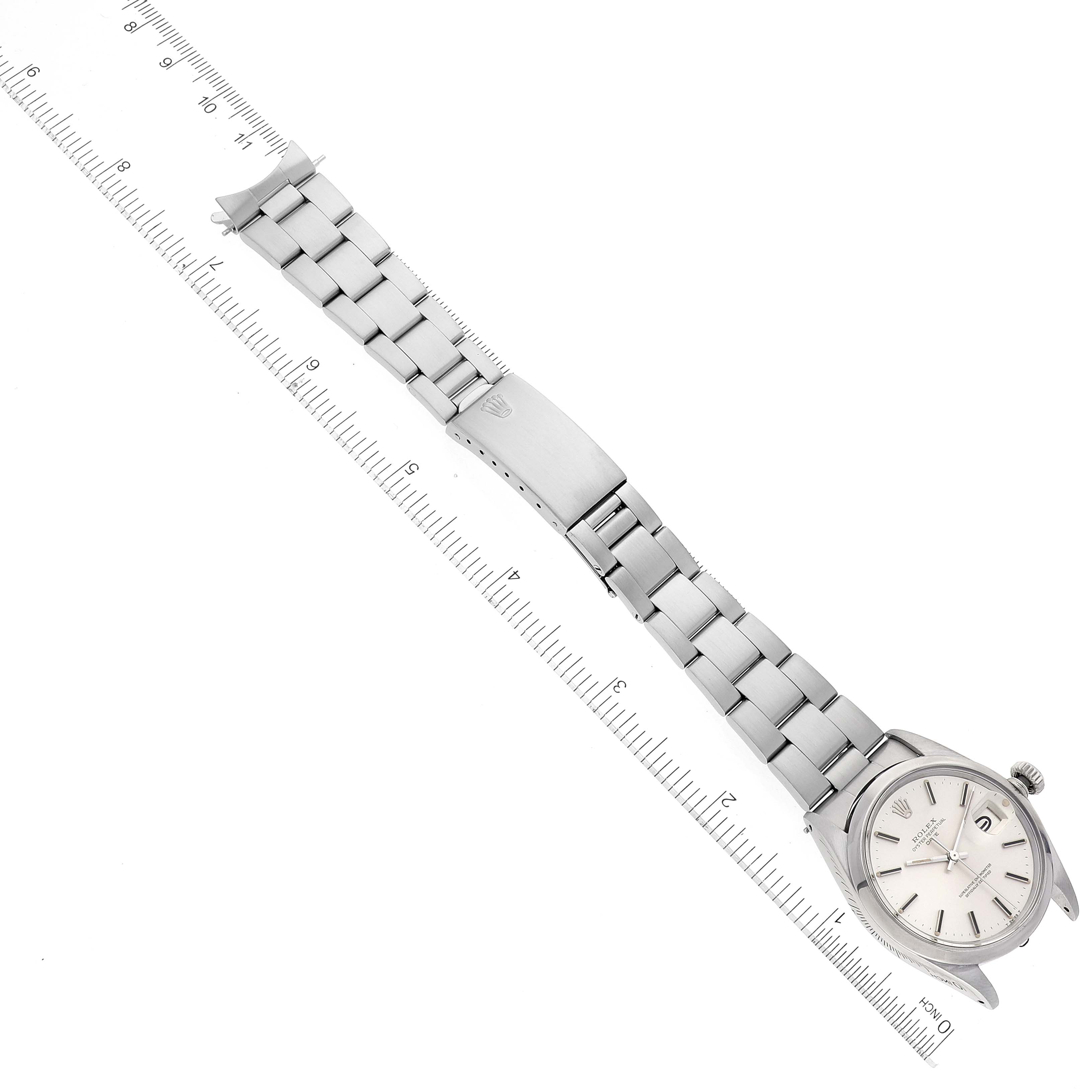 This image shows the Rolex Date 1500 Men's Stainless Steel Silver Dial 1500 Men's Stainless Steel Silver Dial model watch laid out flat with a ruler beside it, displaying the bracelet and watch face.
