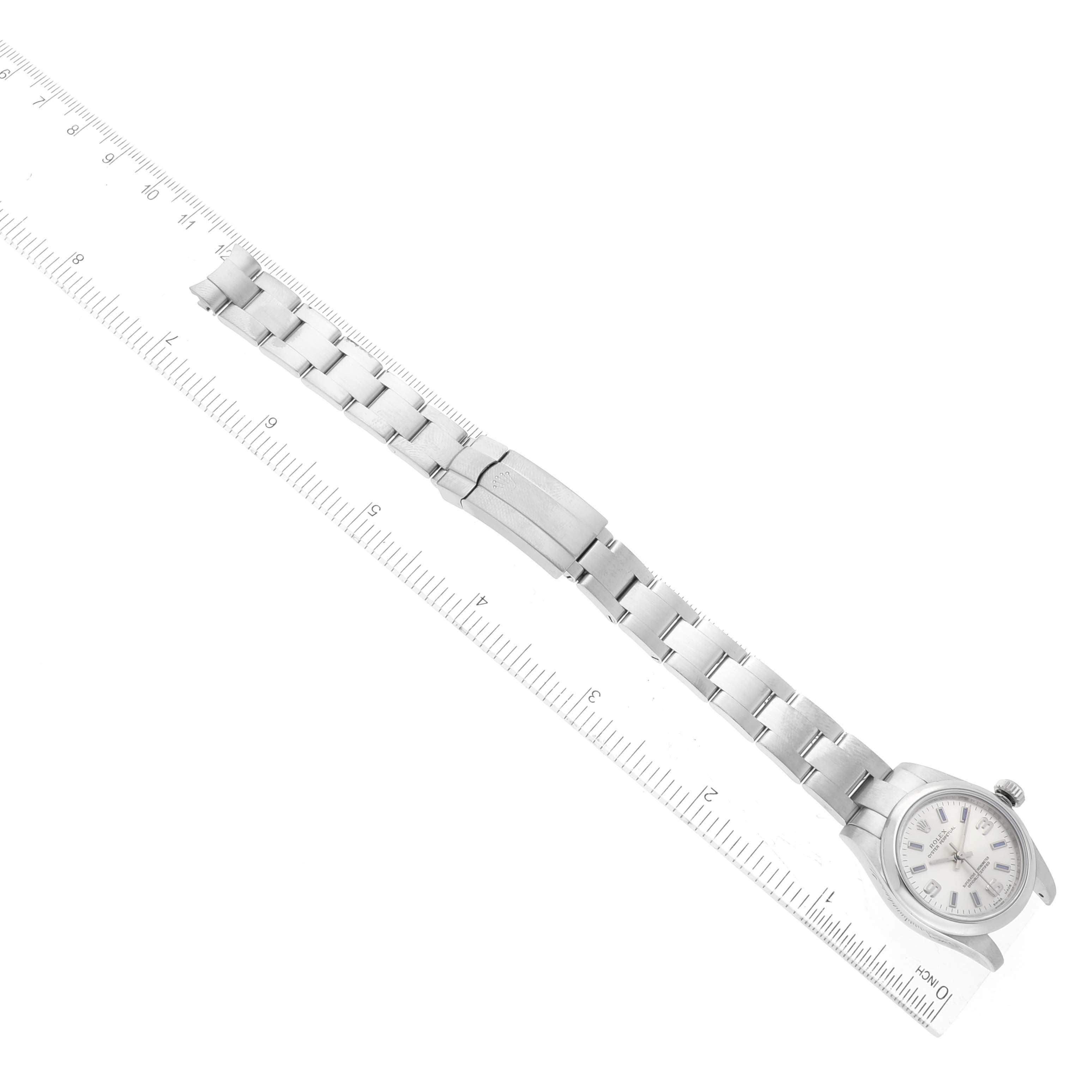 The image shows a Rolex Oyster Perpetual 176200 Women's Stainless Steel Silver Dial 176200 Women's Stainless Steel Silver Dial watch held next to a ruler, displaying the bracelet and case from an aerial view.