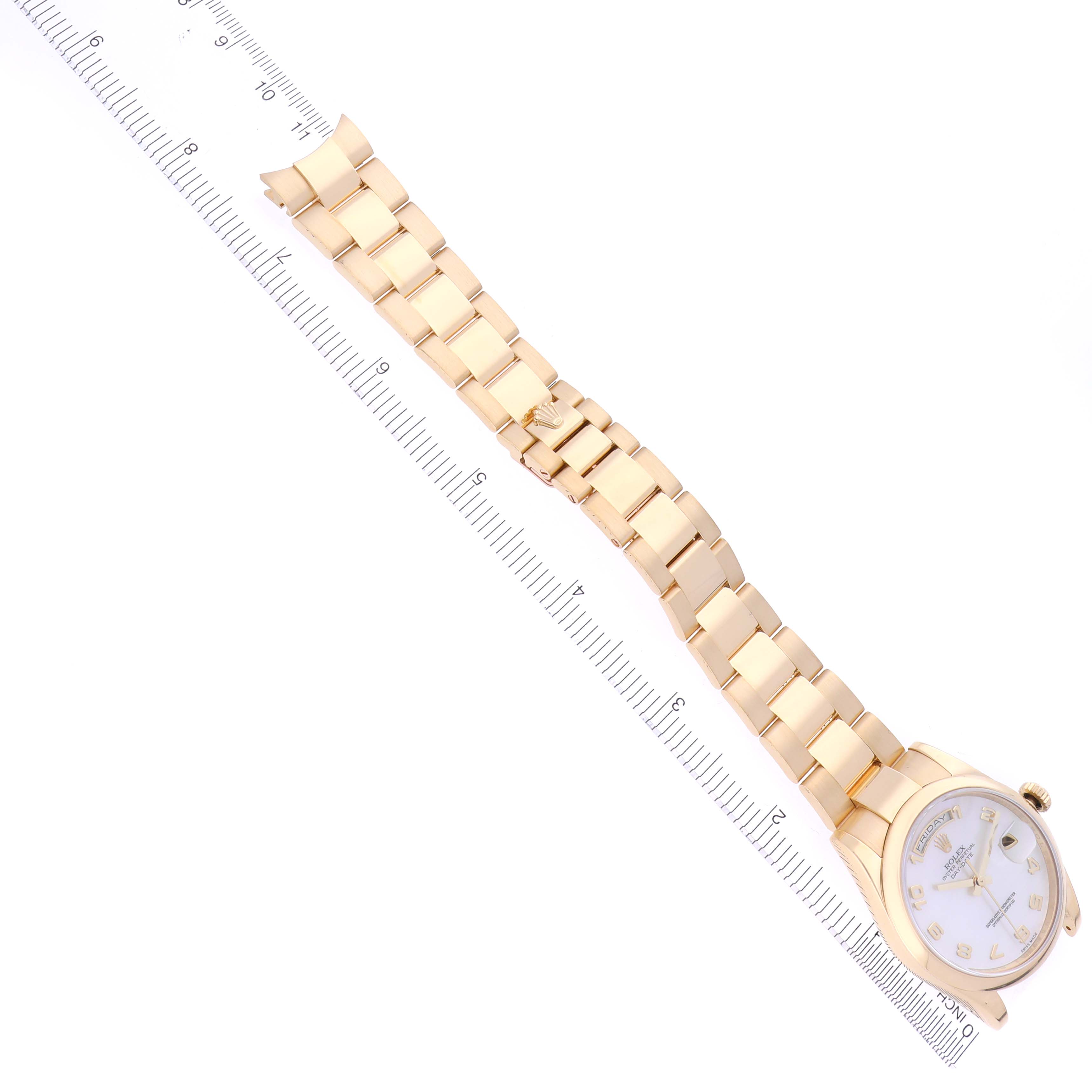 The Rolex President 118208 Men's Yellow Gold Mother of Pearl Dial 118208 Men's Yellow Gold Mother of Pearl Dial model watch is shown from a top-down angle, displaying the gold bracelet and face alongside a ruler for scale.
