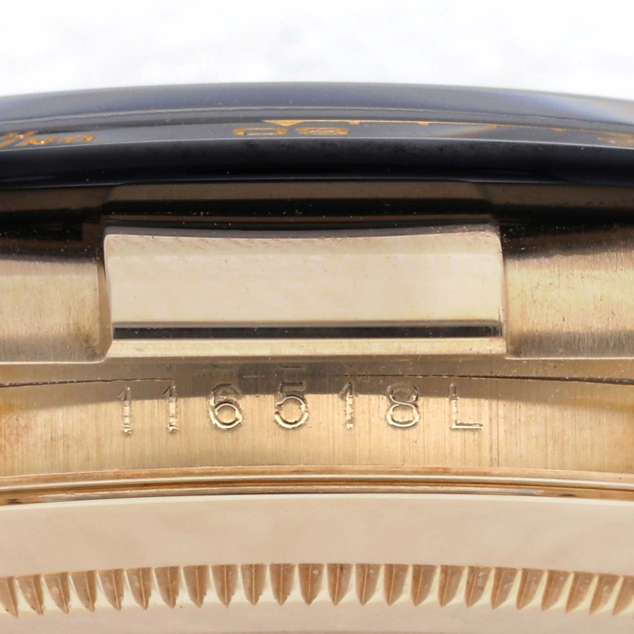 The image shows a side view of the Rolex Daytona 116518 Men's Yellow Gold Black Dial 116518 Men's Yellow Gold Black Dial, focusing on the bezel edge and engraved serial number.