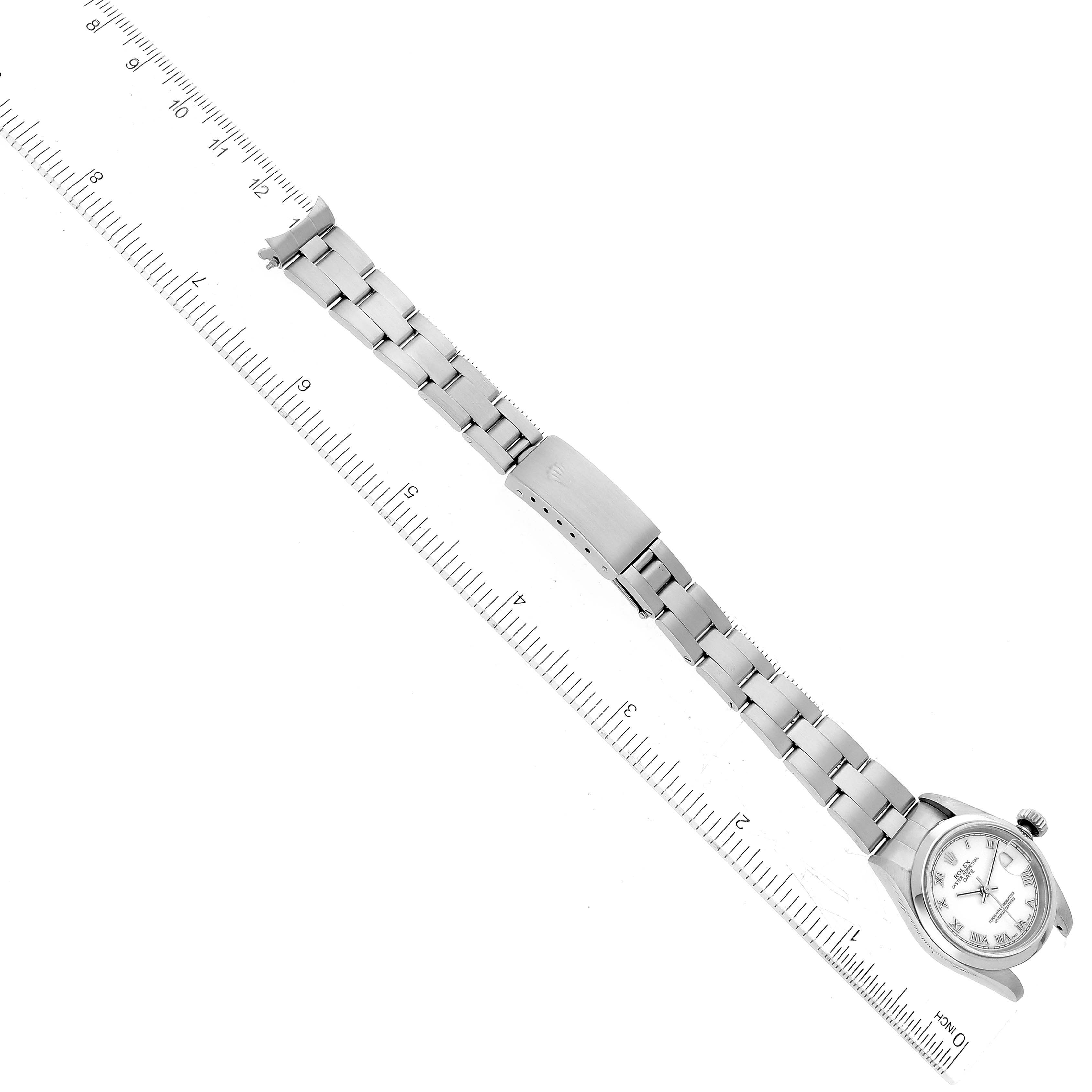 The image shows a Rolex Date 79160 Women's Stainless Steel White Dial 79160 Women's Stainless Steel White Dial model watch lying flat, fully extended, with its face, bracelet, and clasp visible against a ruler for scale.