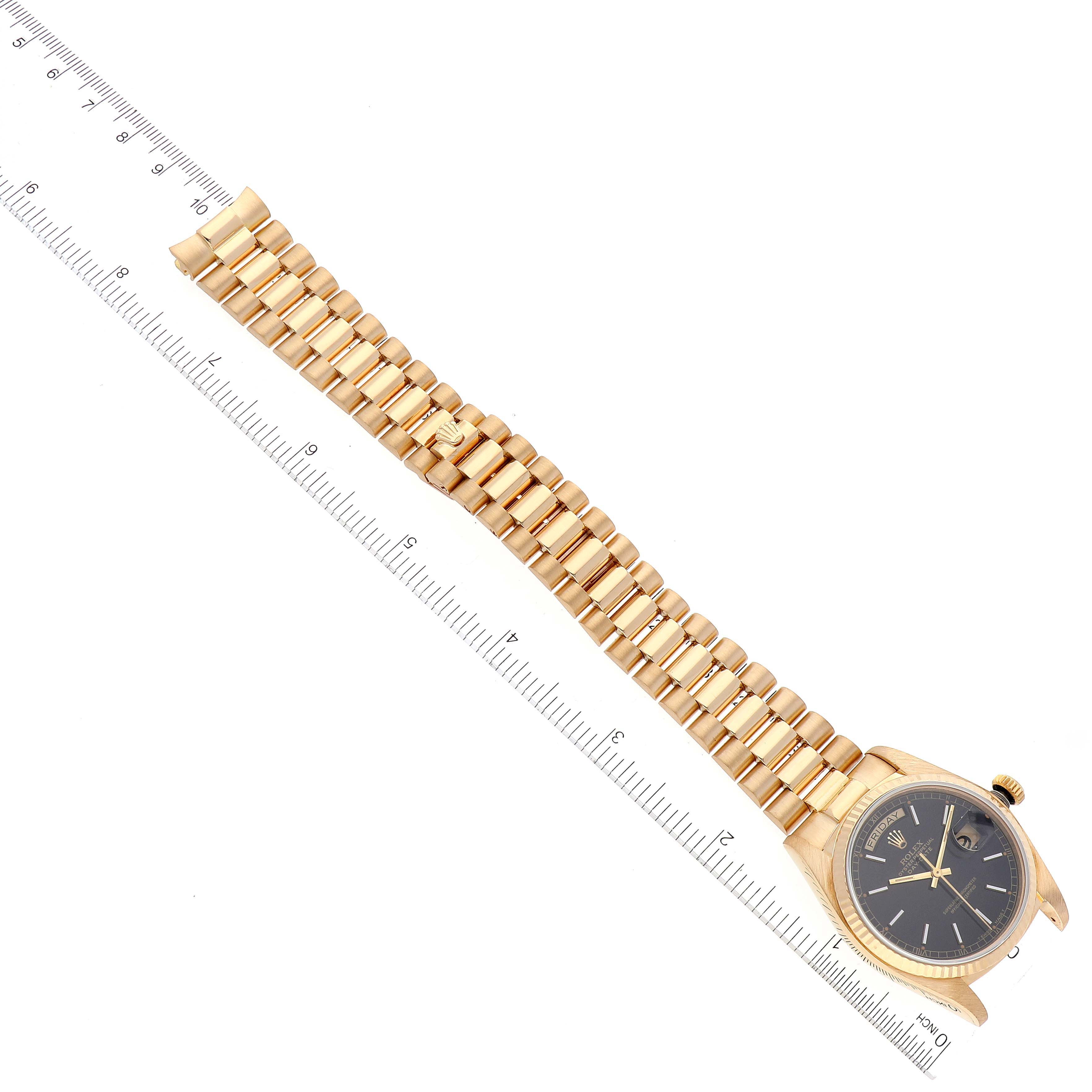 The image shows a gold Rolex President 18038 Men's Yellow Gold Black Dial 18038 Men's Yellow Gold Black Dial model watch laid flat with both the face and bracelet visible, alongside a measuring ruler.