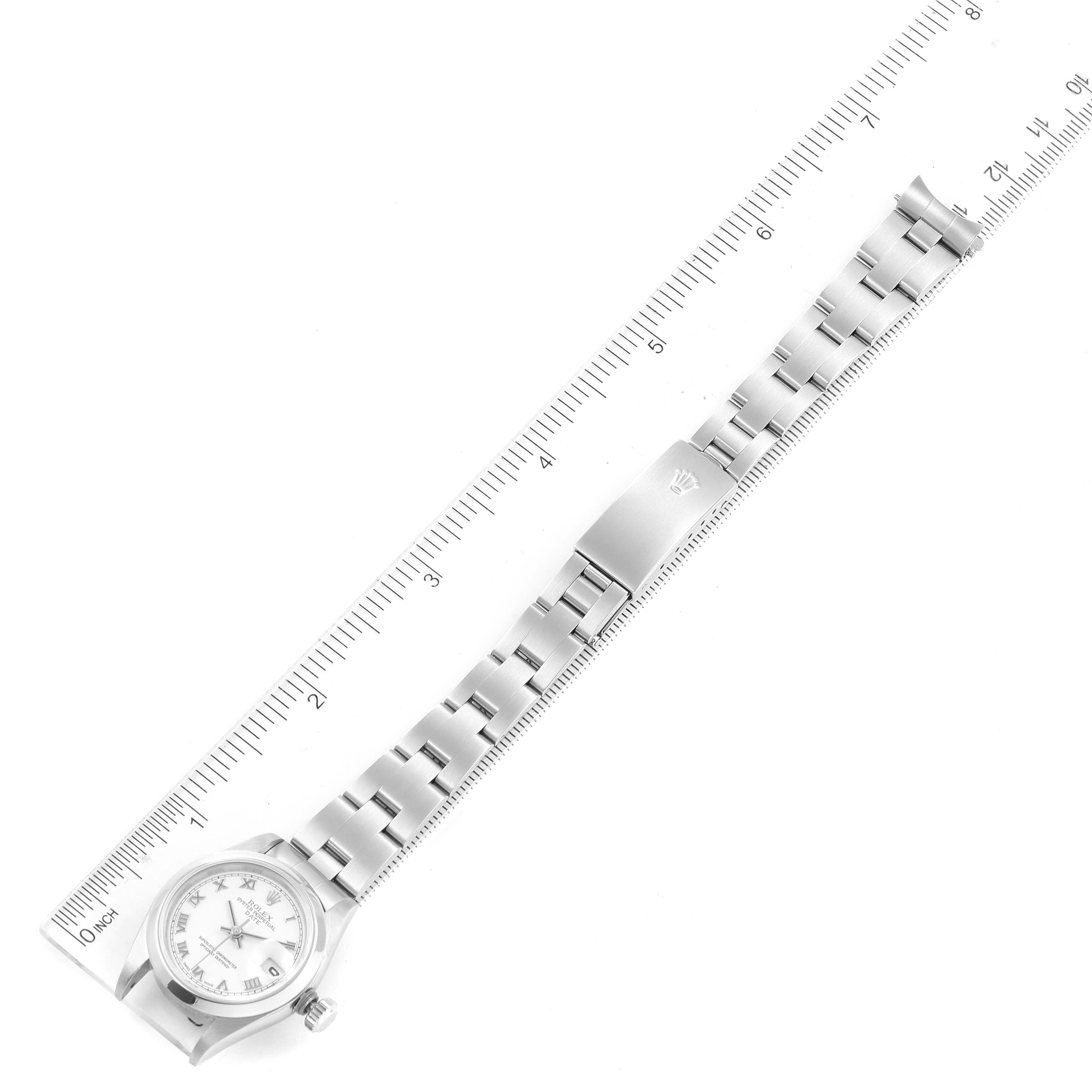 The image shows a top-down view of a Rolex Date 79160 Women's Stainless Steel White Dial 79160 Women's Stainless Steel White Dial model watch with its full bracelet and a portion of a ruler for scale.
