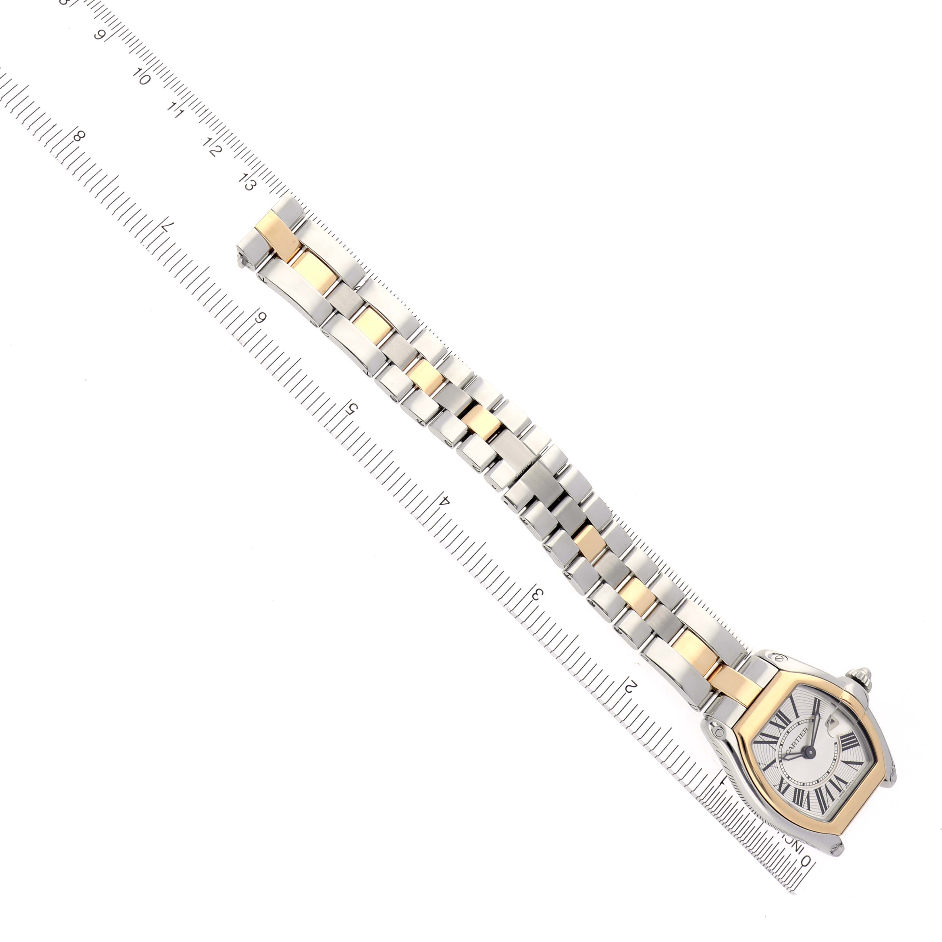 The Cartier Roadster W62026Y4 Women's Steel and Gold (two tone) Silver Dial W62026Y4 Women's Steel and Gold (two tone) Silver Dial watch is shown diagonally from above, displaying the face and full bracelet alongside a ruler.