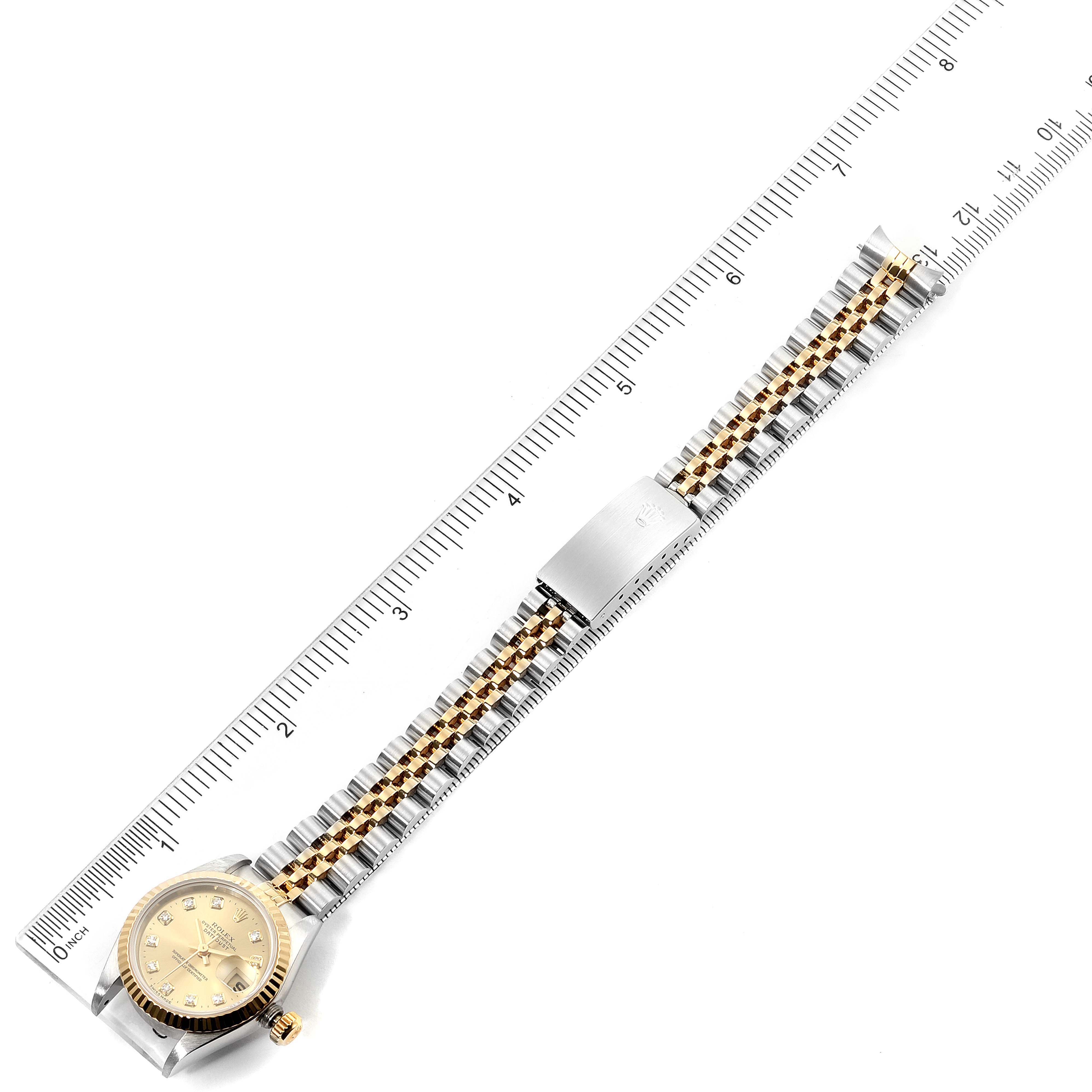 The image displays a full view of the Rolex Datejust 69173 Women's Steel and Gold (two tone) Champagne Dial 69173 Women's Steel and Gold (two tone) Champagne Dial watch placed alongside a ruler, showing its bracelet, clasp, and dial.