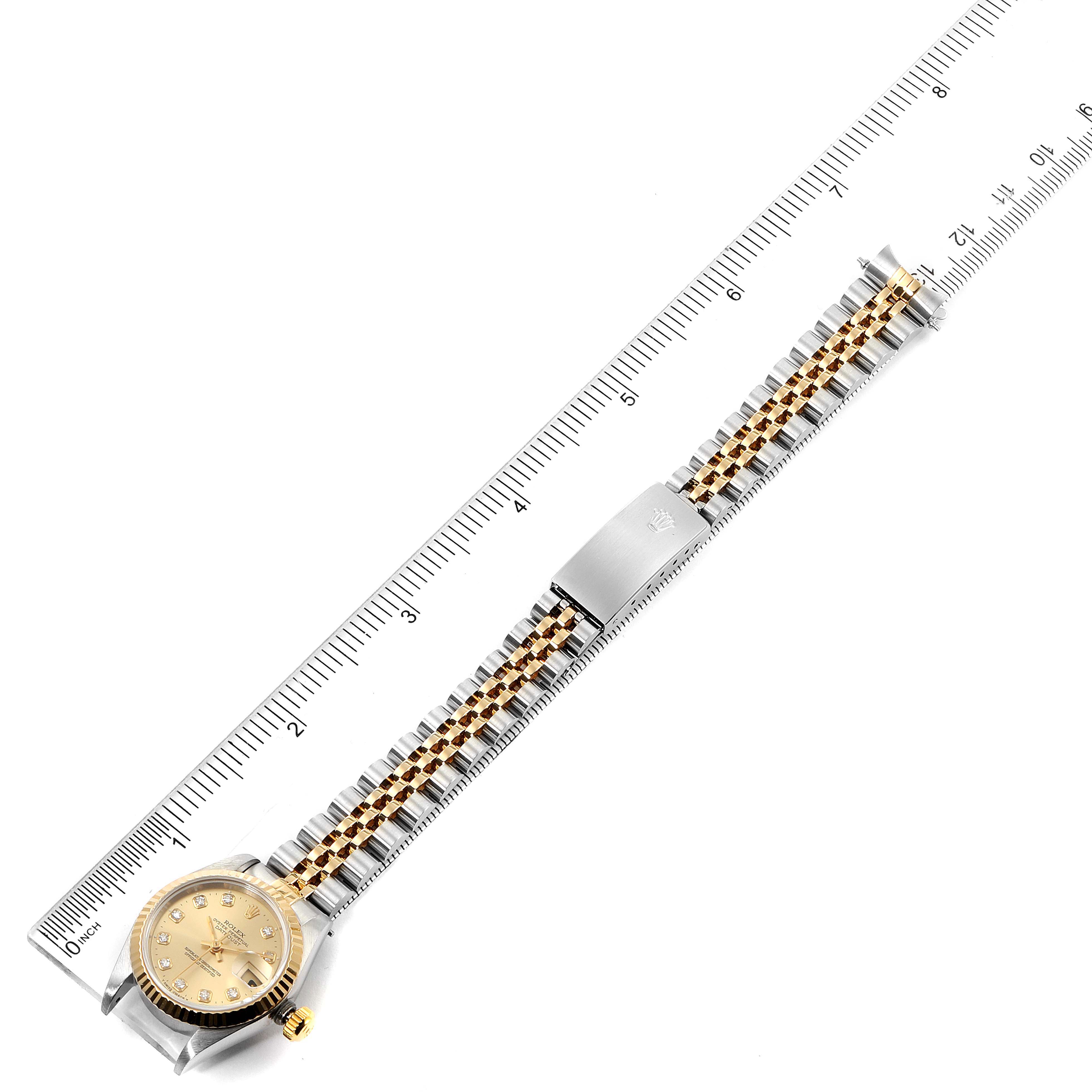 The Rolex Datejust 69173 Women's Steel and Gold (two tone) Champagne Dial 69173 Women's Steel and Gold (two tone) Champagne Dial watch is shown from above, highlighting the dial, bracelet, clasp, and positioned against a ruler for scale.