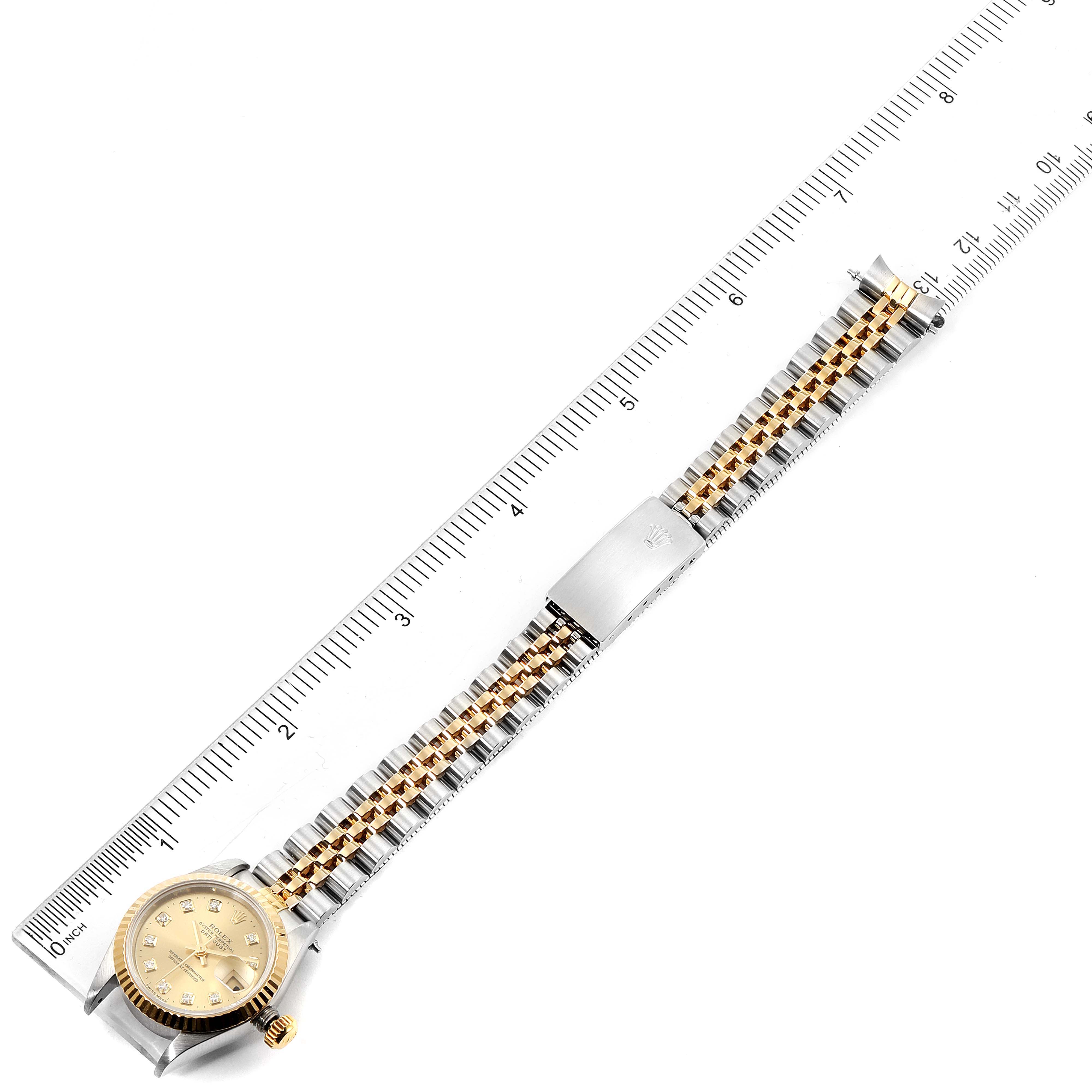 This image shows a top-down view of a Rolex Datejust 69173 Women's Steel and Gold (two tone) Champagne Dial 69173 Women's Steel and Gold (two tone) Champagne Dial watch, including the entire band, clasp, and face, placed next to a ruler.