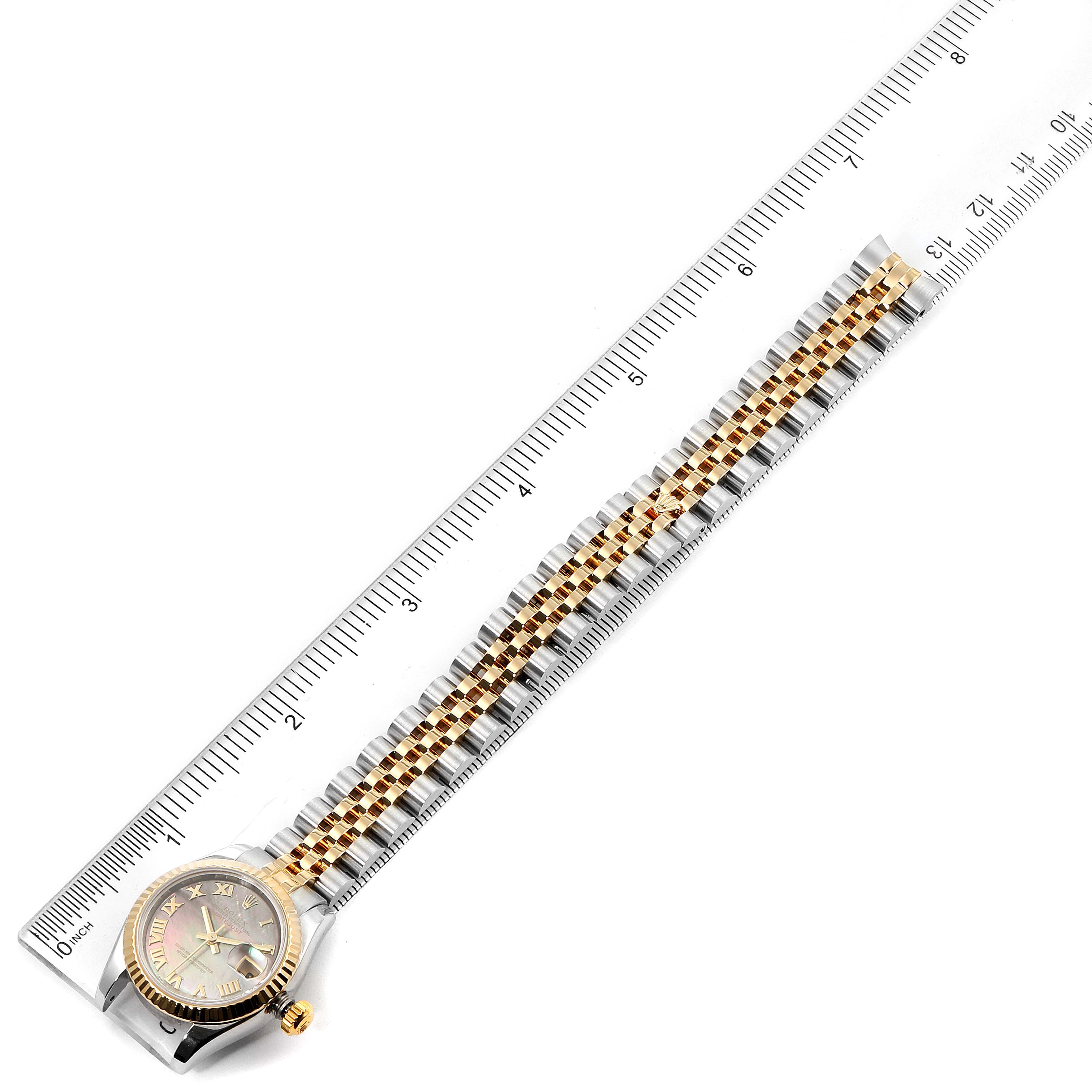 The image shows a top-down view of a Rolex Datejust 179173 Women's Steel and Gold (two tone) Mother of Pearl Dial 179173 Women's Steel and Gold (two tone) Mother of Pearl Dial watch resting next to a ruler, displaying its bracelet and face.