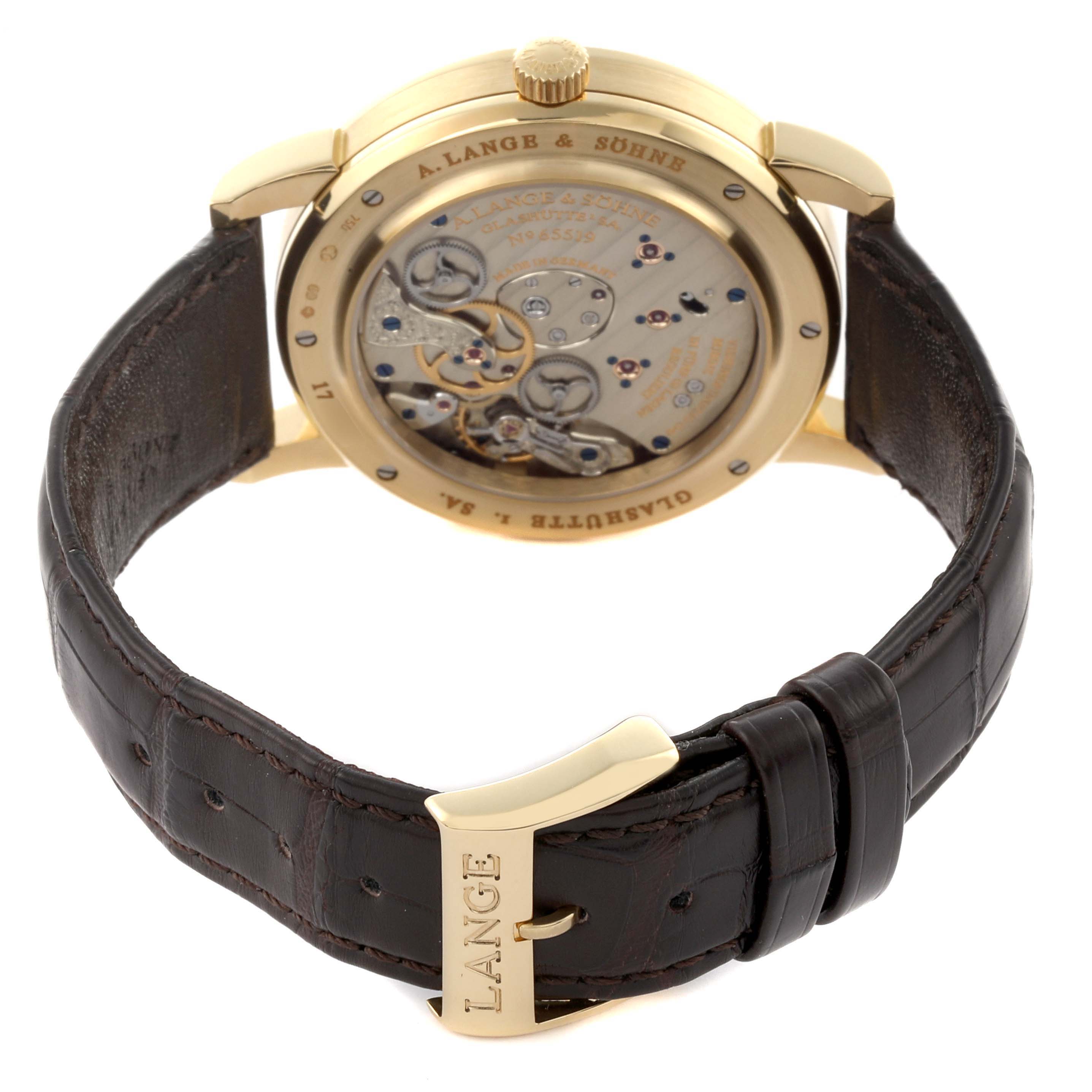 The image shows a rear view of the A. Lange & Sohne Lange 1 116.021 Men's Yellow Gold Silver Dial, highlighting its movement and brown leather strap.
