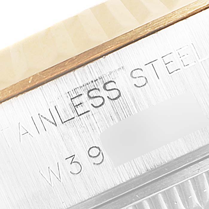 This close-up image of the Rolex Datejust 69173 Women's Steel and Gold (two tone) Champagne Dial 69173 Women's Steel and Gold (two tone) Champagne Dial model shows the stainless steel casing with partial serial number and some wooden surfaces.