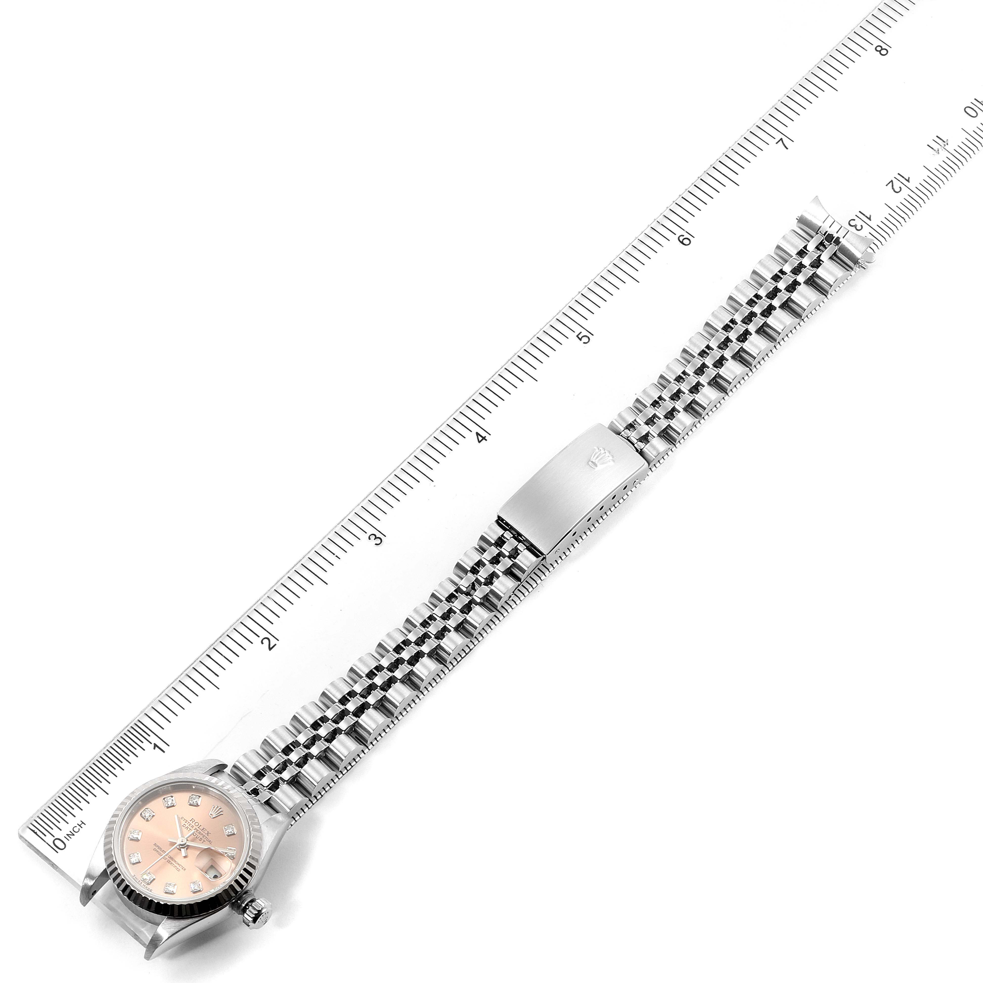 The image showcases a Rolex Datejust 79174 Women's Stainless Steel Pink Dial 79174 Women's Stainless Steel Pink Dial watch from a top-down angle, displaying its face, bracelet, and clasp alongside a ruler for scale.
