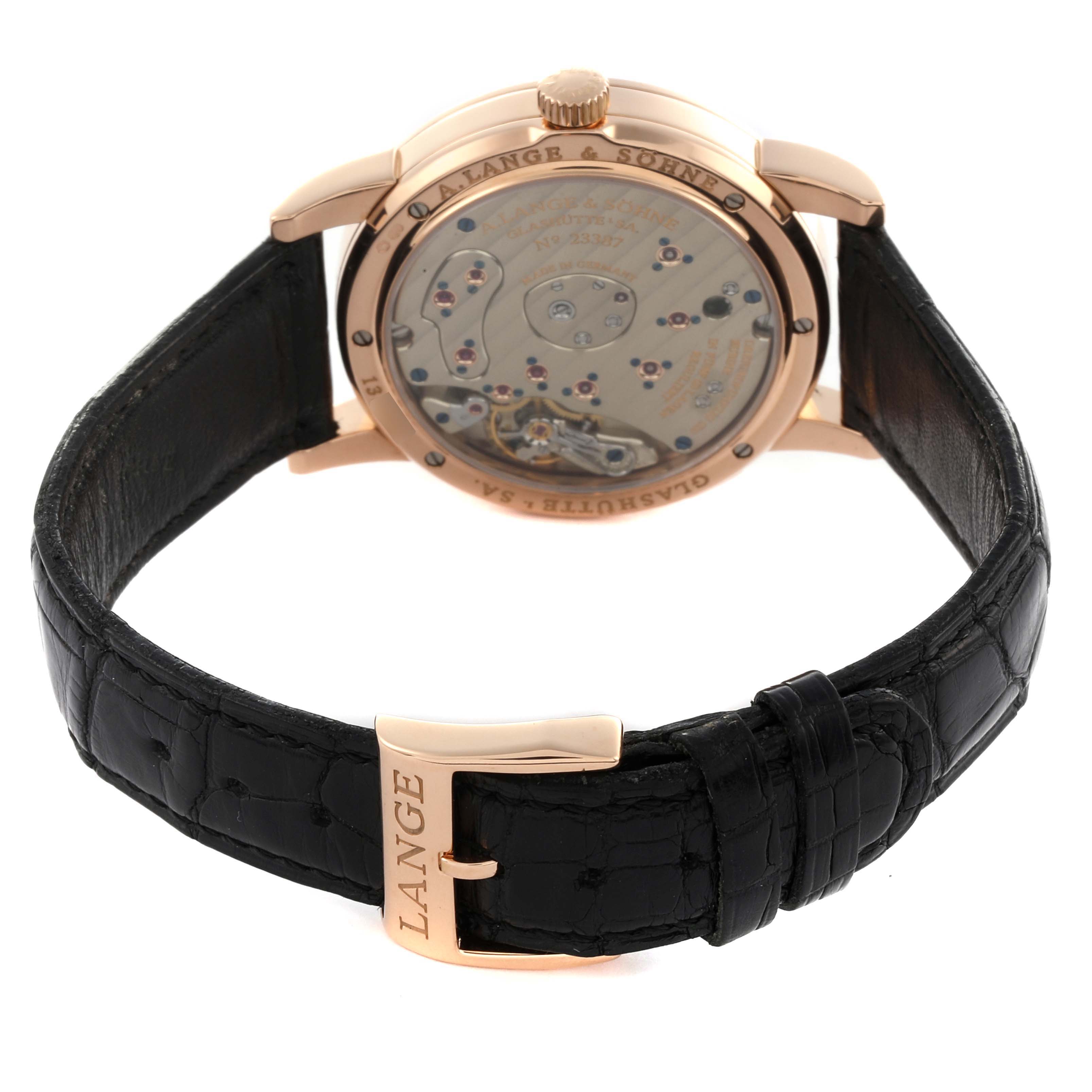 The A. Lange & Sohne Lange 1 101.031 Men's Rose Gold Black Dial watch is shown from the back, revealing its movement and featuring a black leather strap.