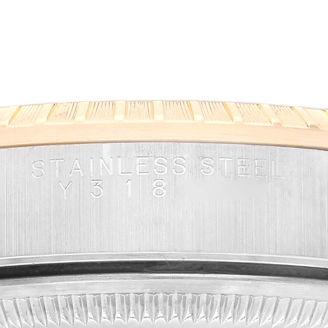 The image shows a close-up of the side of a Rolex Date 15223 Men's Steel and Gold (two tone) Blue Dial 15223 Men's Steel and Gold (two tone) Blue Dial watch, focusing on the stainless steel engraving and part of the bezel.