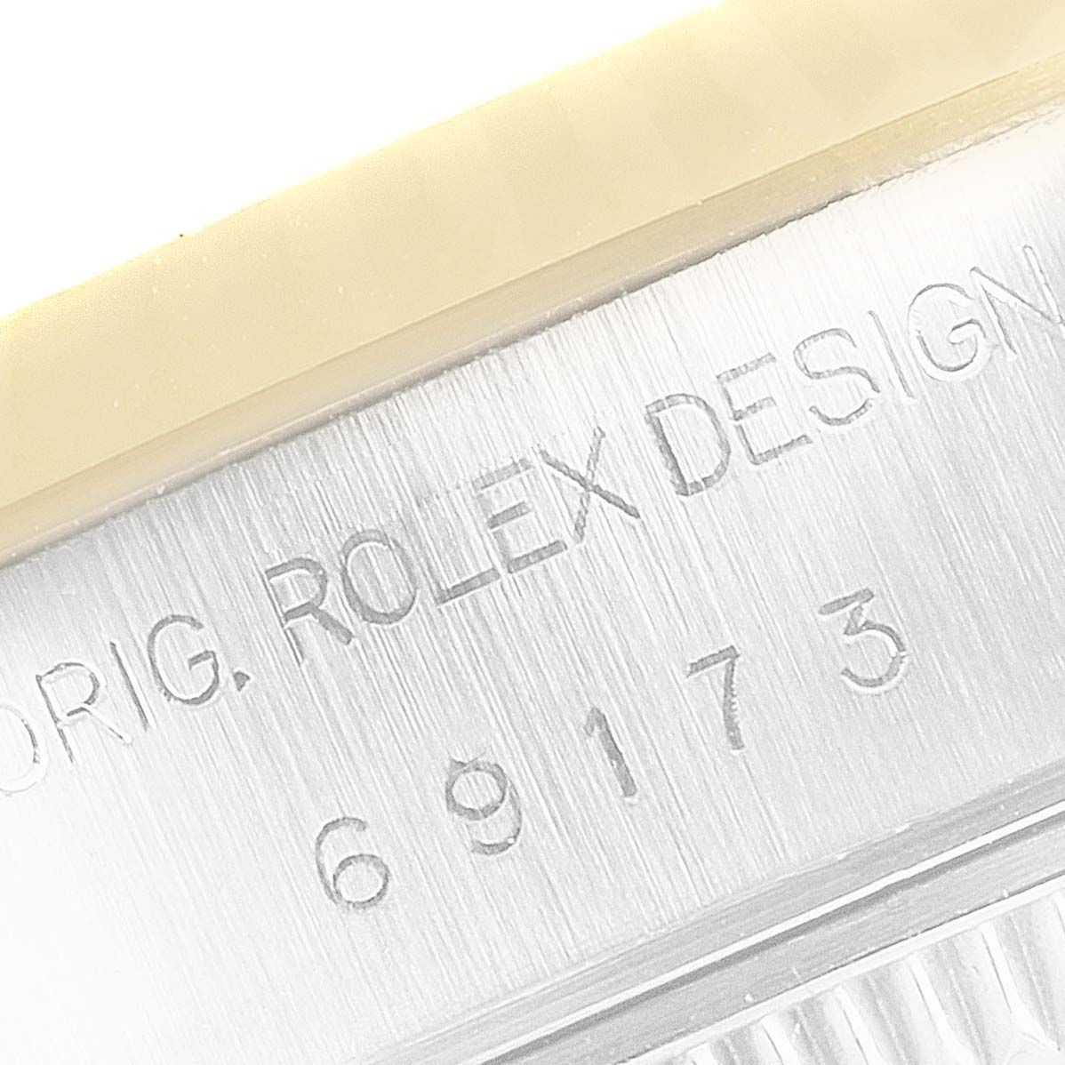 This close-up image shows the case side of a Rolex Datejust 69173 Women's Steel and Gold (two tone) Champagne Dial 69173 Women's Steel and Gold (two tone) Champagne Dial watch, featuring the engraved "ROLEX DESIGN" text and model number.