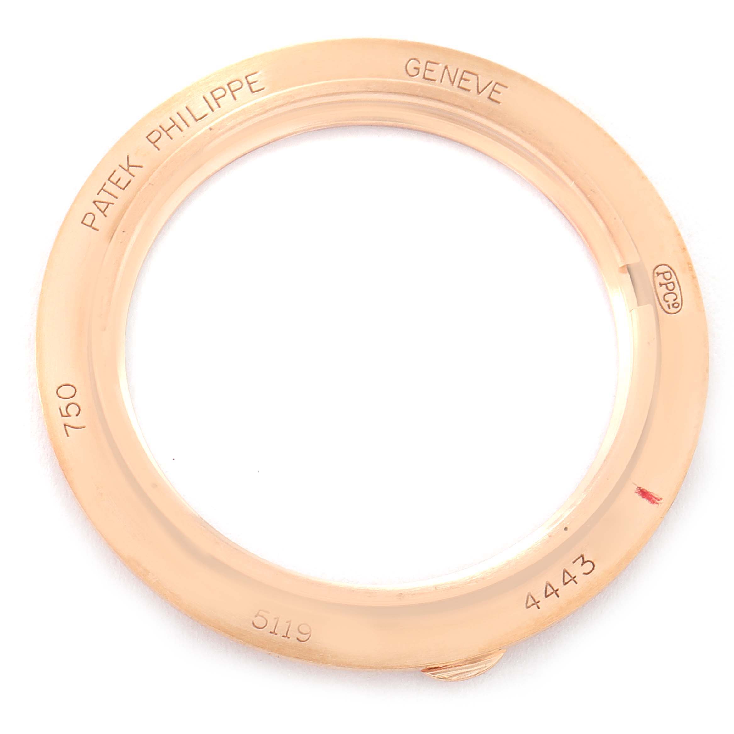 The image shows a gold bezel of a Patek Philippe Calatrava 5119R Men's Rose Gold White Dial 5119R Men's Rose Gold White Dial model watch, featuring engravings and hallmark stamps.