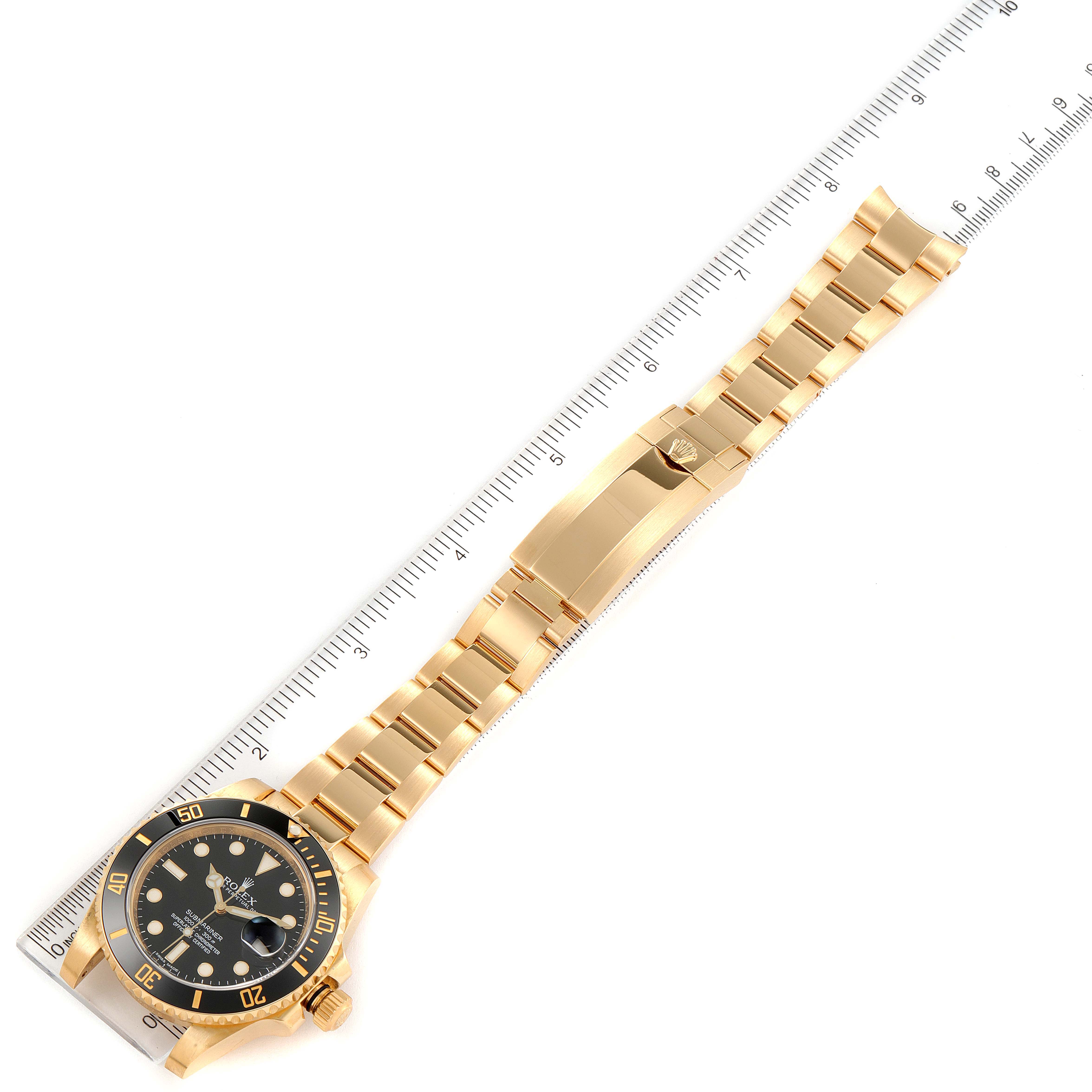 The image shows a Rolex Submariner 116618 Men's Yellow Gold Black Dial 116618 Men's Yellow Gold Black Dial watch lying flat with its bracelet fully extended alongside a ruler.