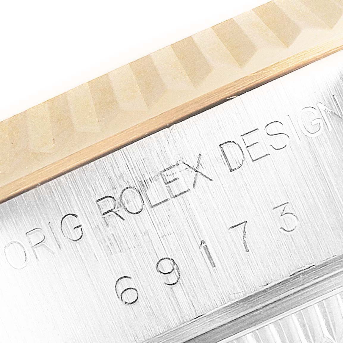 This close-up angle of the Rolex Datejust 69173 Women's Steel and Gold (two tone) Champagne Dial 69173 Women's Steel and Gold (two tone) Champagne Dial watch shows the fluted bezel and the engraved serial and model numbers on the case.