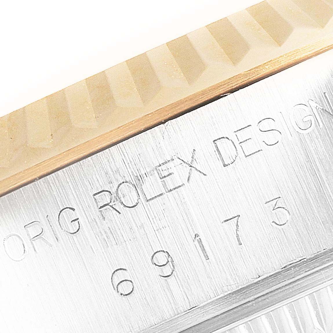 This close-up image of a Rolex Datejust 69173 Women's Steel and Gold (two tone) Champagne Dial 69173 Women's Steel and Gold (two tone) Champagne Dial watch shows part of the fluted bezel and engraved case.