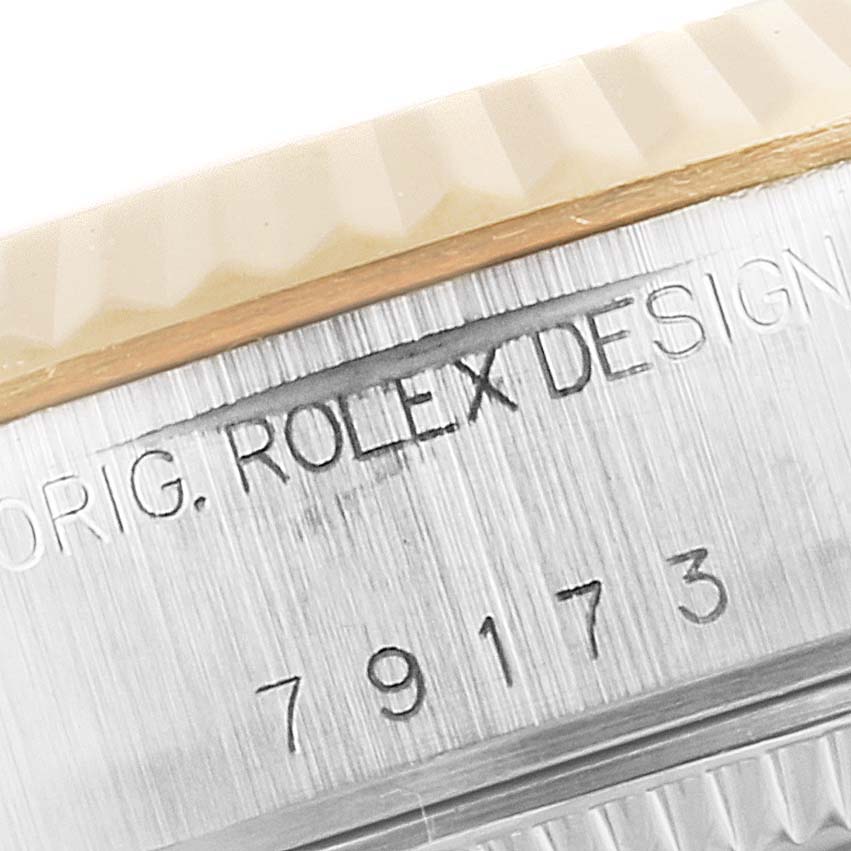 The image shows a close-up angle of the bezel and engravings on the side of a Rolex Datejust 79173 Women's Steel and Gold (two tone) Mother of Pearl Dial 79173 Women's Steel and Gold (two tone) Mother of Pearl Dial watch case.