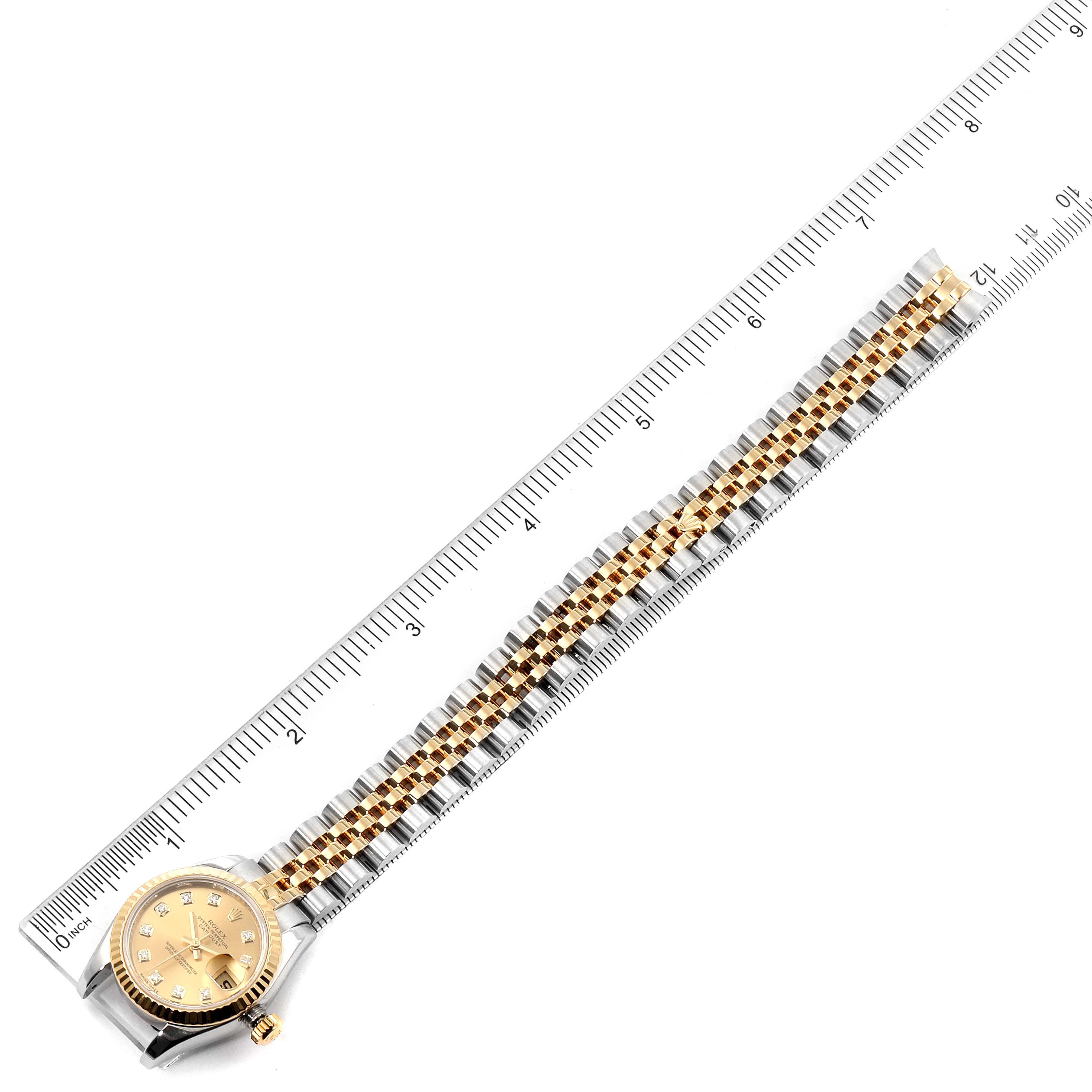 The image shows a top-down view of a Rolex Datejust 179173 Women's Steel and Gold (two tone) Champagne Dial 179173 Women's Steel and Gold (two tone) Champagne Dial watch with its band aligned along a ruler.